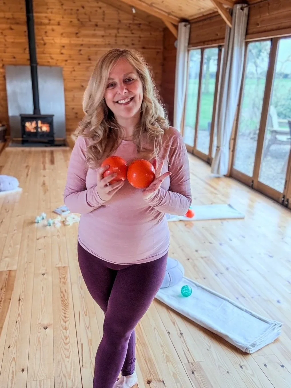 Level 4 Franklin Method® Educator Sarah Pritchard, standing with orange small balls in the Garden Room at Newton Meadows. Sarah offers specialist somatic movement training and psoas release for practitioners in Shrewsbury, Shropshire.