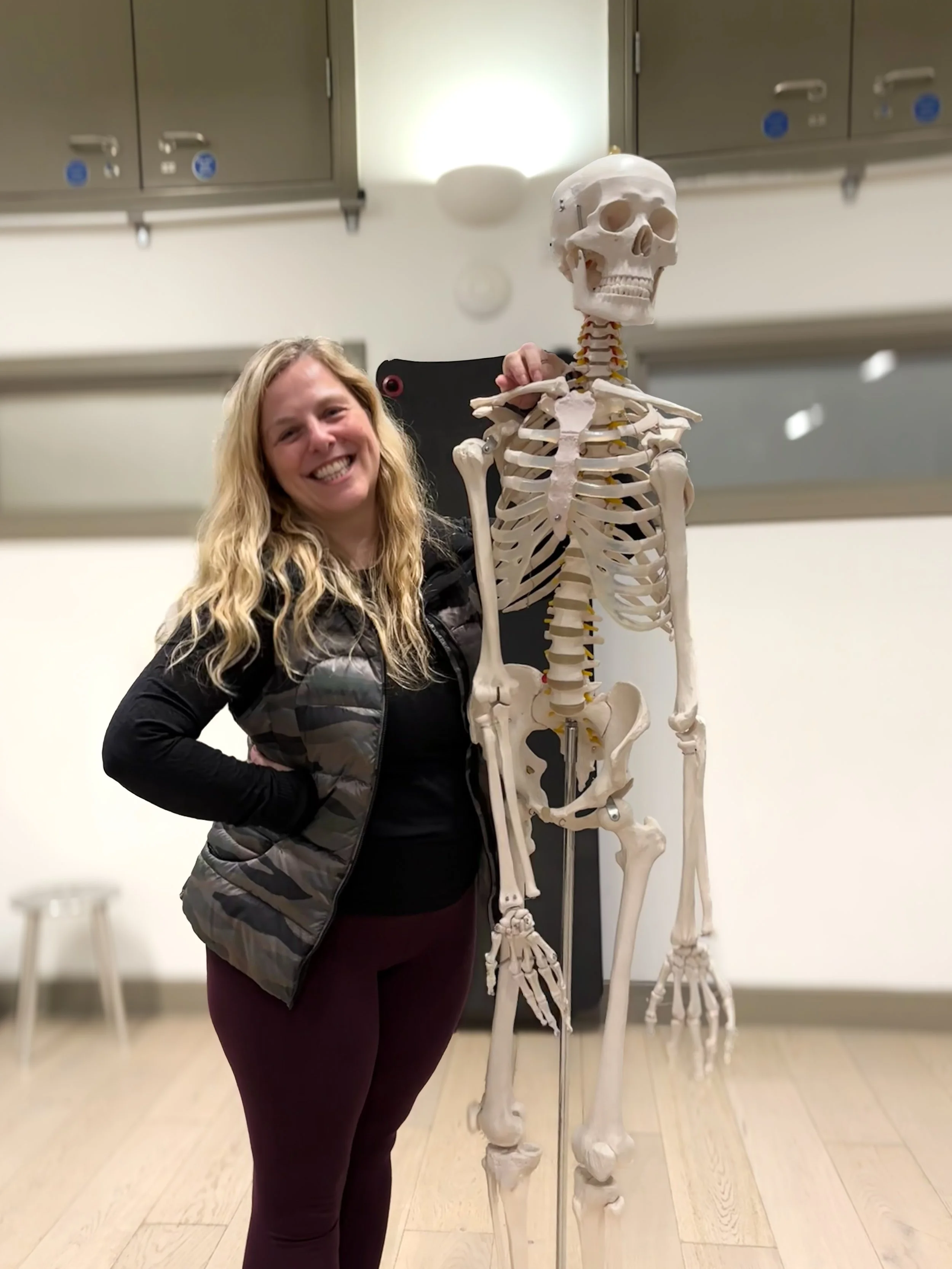Sarah Pritchard, ISMETA Reg Master Somatic Movement Therapist & Educator (MSMT/MSME) and Buff Bones® Faculty member, posing with an anatomical skeleton model, offering osteoporosis exercise for midlife women in regulated somatics and Pilates.