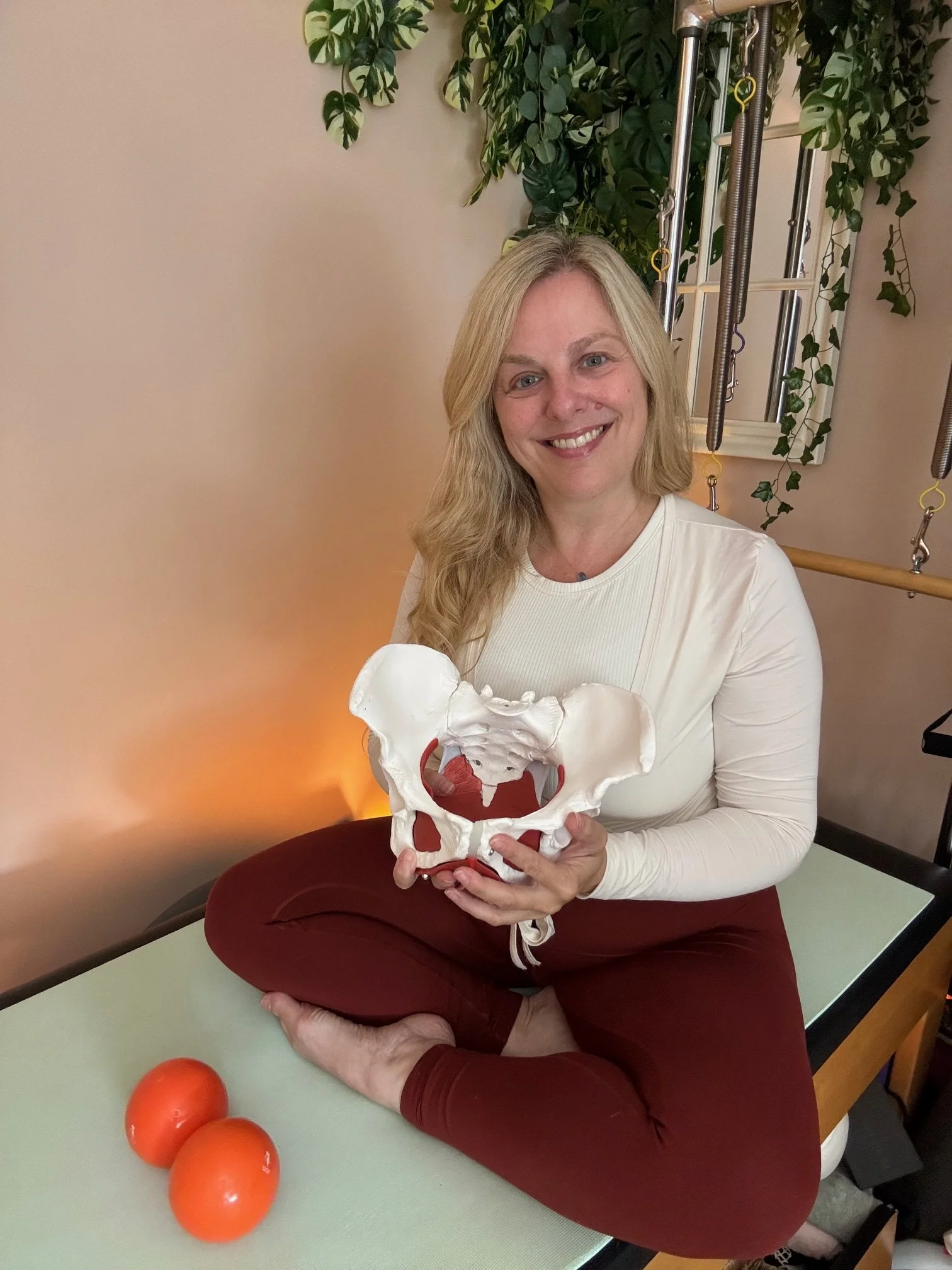Sarah Pritchard, pre and postnatal Pilates specialist in Birmingham, holding an anatomical pelvic model for pelvic floor re-education.