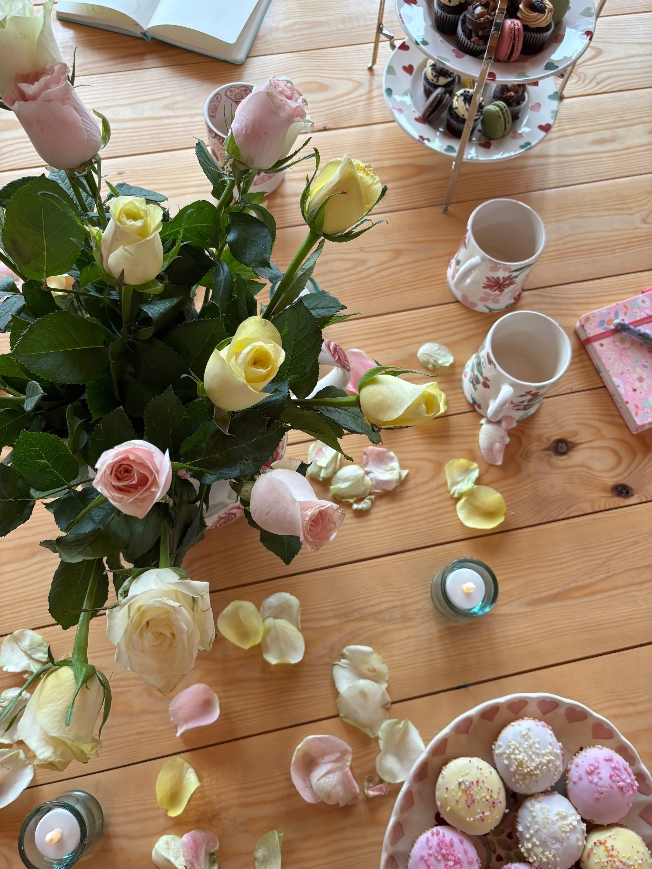 Soft somatic sanctuary at Newton Meadows, Shrewsbury. Featuring fresh roses, candlelight, and Emma Bridgewater pottery on a natural pine floor—a restorative environment designed by Sarah Pritchard for midlife women's nervous system regulation