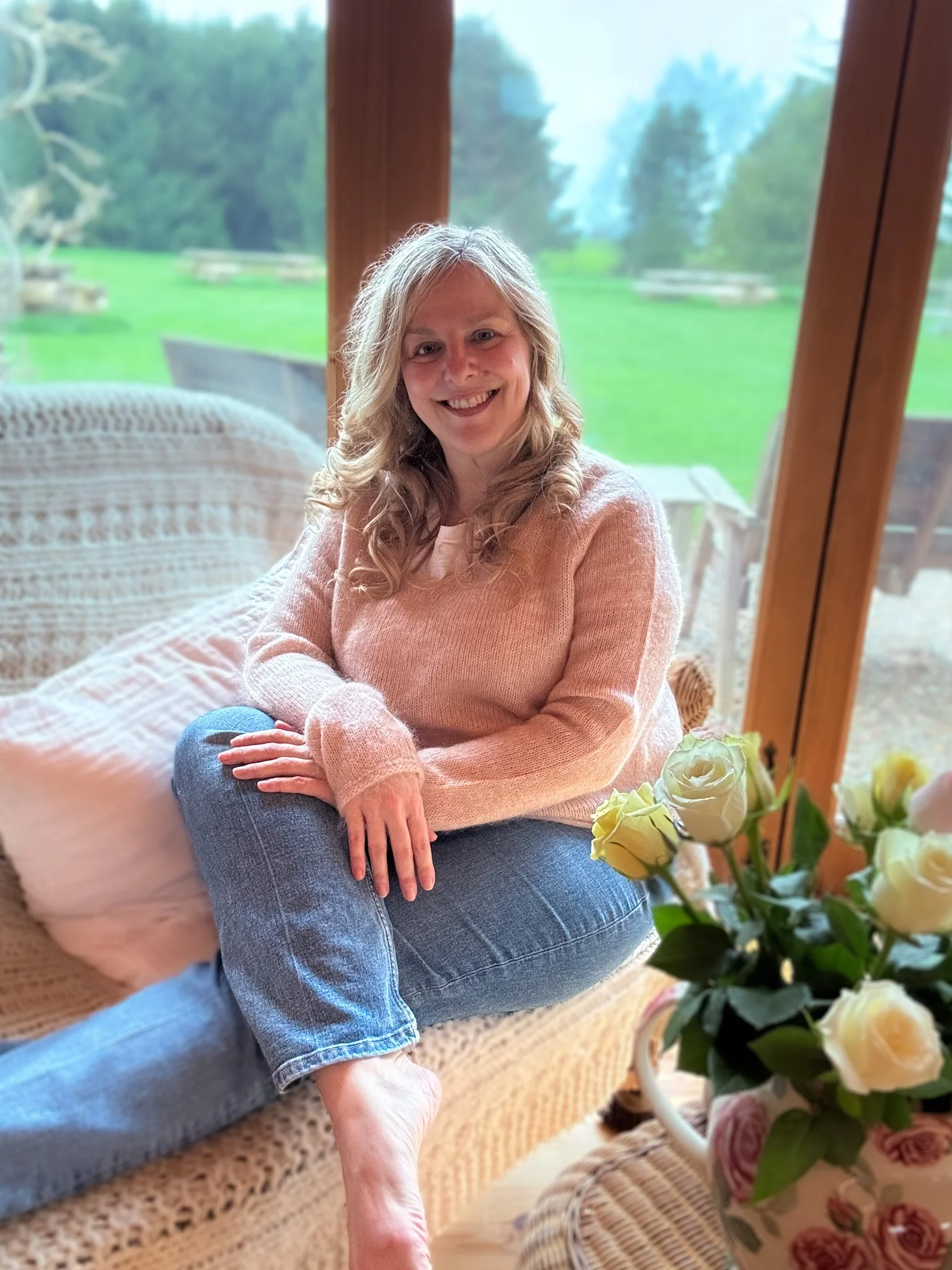 Sarah Pritchard, Master Somatic Movement Therapist, enjoying the sunlit studio at Newton Meadows Shrewsbury, overlooking pine trees and expansive gardens during a somatic retreat.