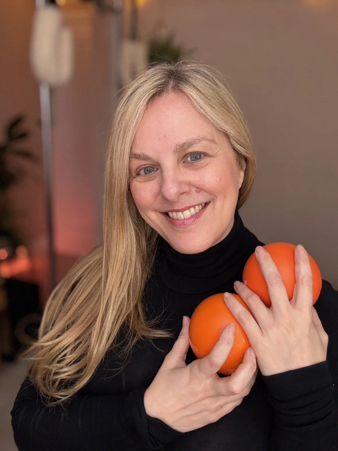 Sarah Pritchard, ISMETA Registered Master Somatic Movement Therapist and Educator (MSMT/MSME), holding orange Franklin Method self-myofascial release balls in her virtual studio