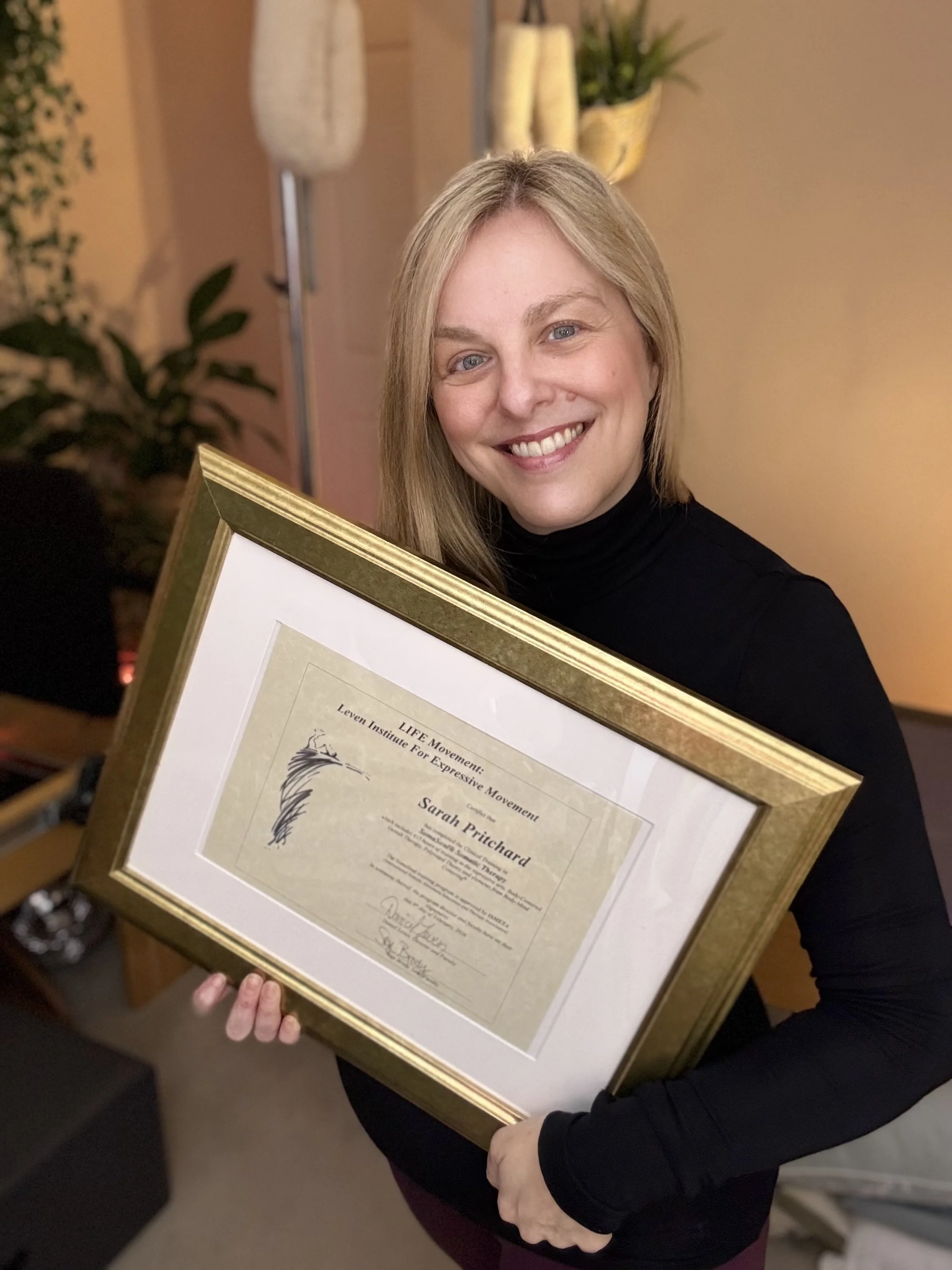 Sarah Pritchard holding her 1st Generation SomaSoul® Somatic Therapist certificate, trained directly by Dan Leven ISMETA Registered Master Somatic Movement Therapist