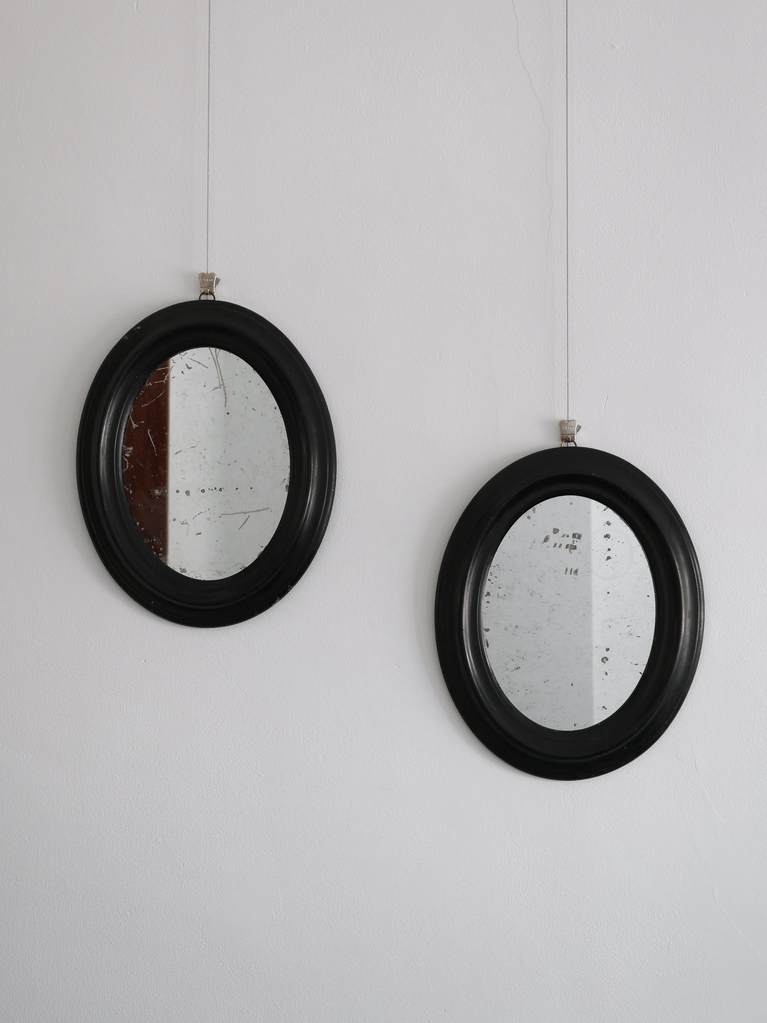 Pair of Ebonised Oval Mirrors