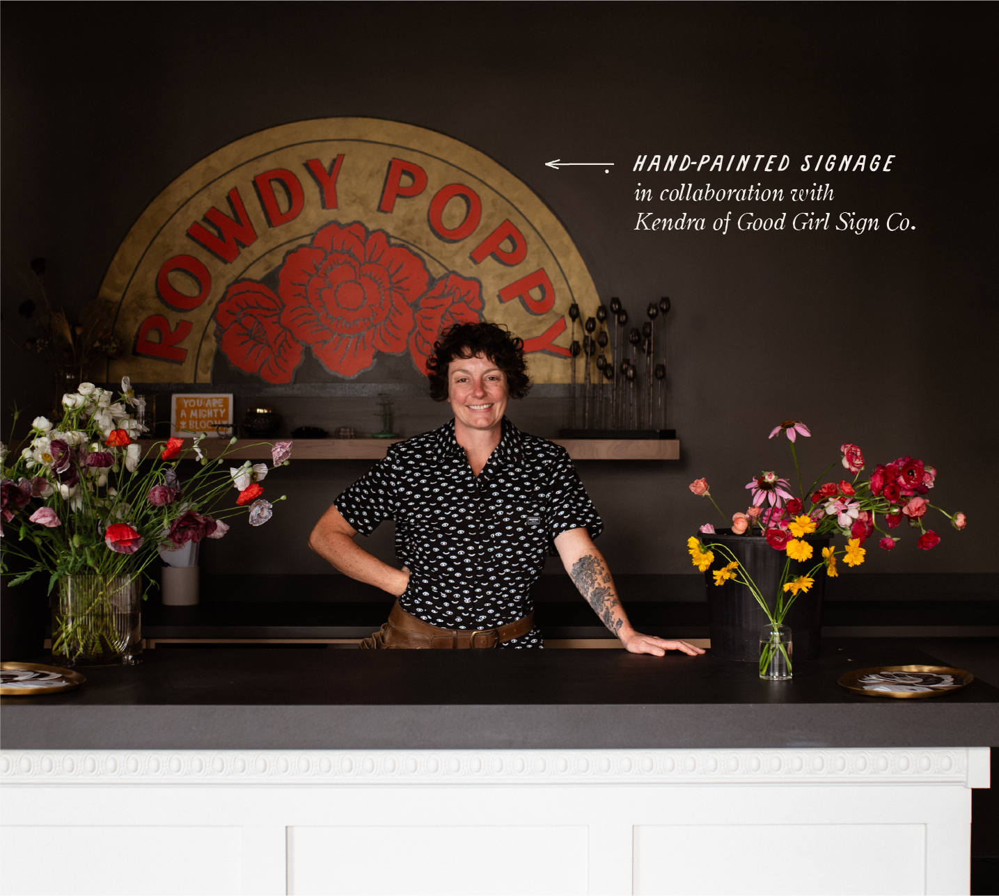 Owner Kim Zimmerman stands in front of hand-painted sign by Good Girl Line & Sign designed by Paper Laundry.