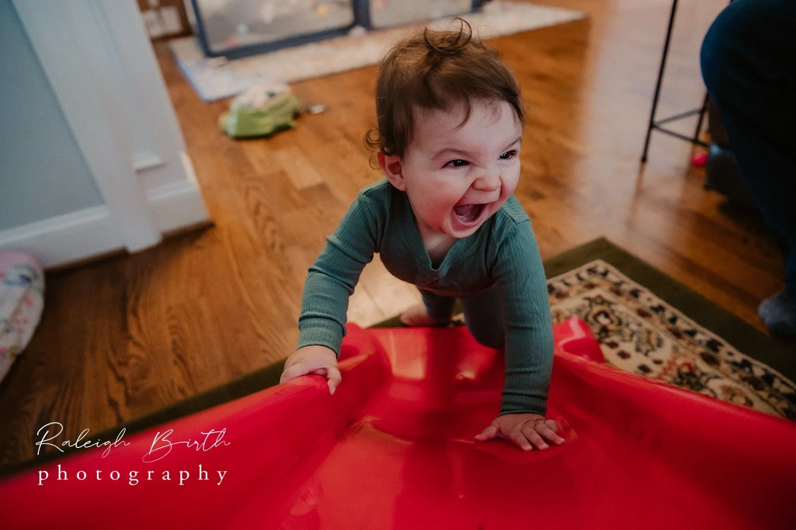small child plays on red slide in living room close up on excited expression