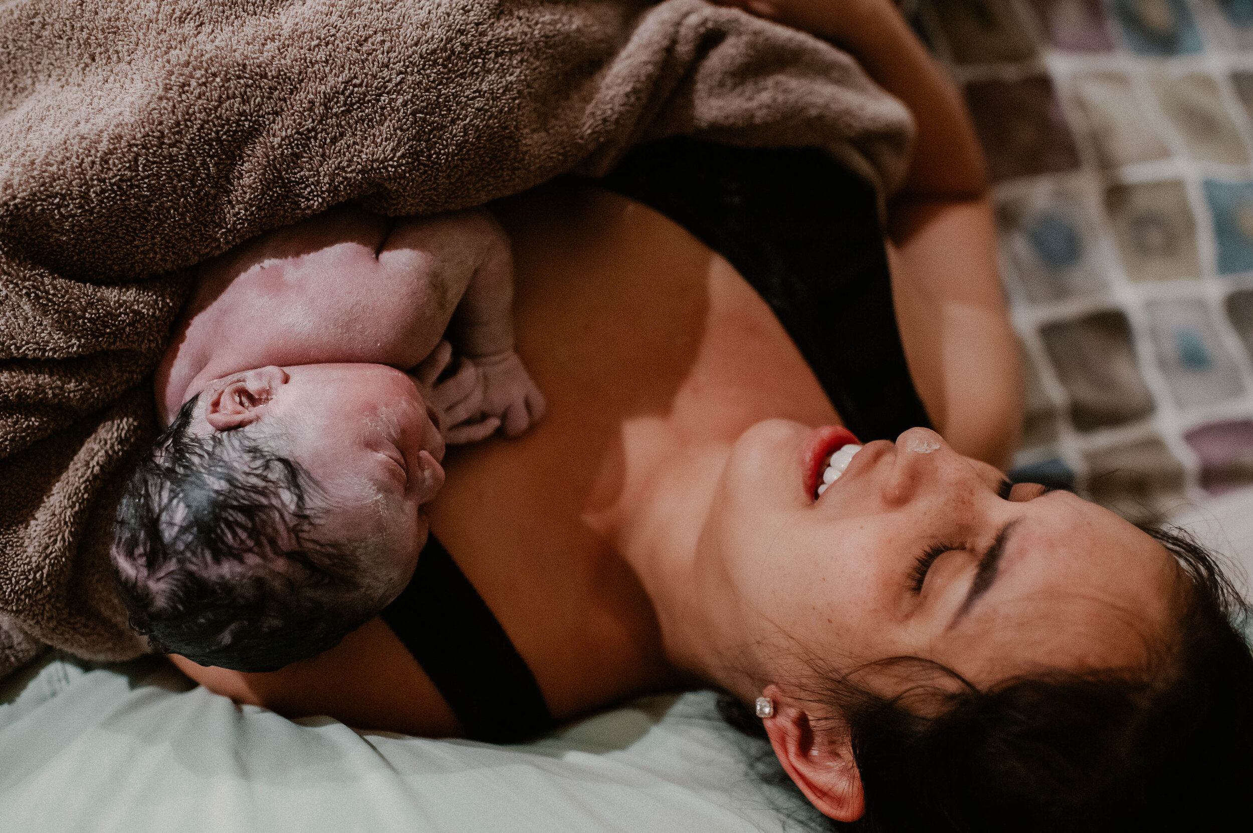 close up of mother and newborn on bed after birth at home
