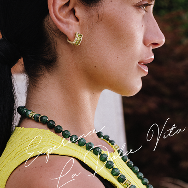 Profile of a beautiful woman in yellow sleeveless dress wearing Miseno chunky necklace and gold huggie earring with words written in script "Experience La Dolce Vita" at an angle