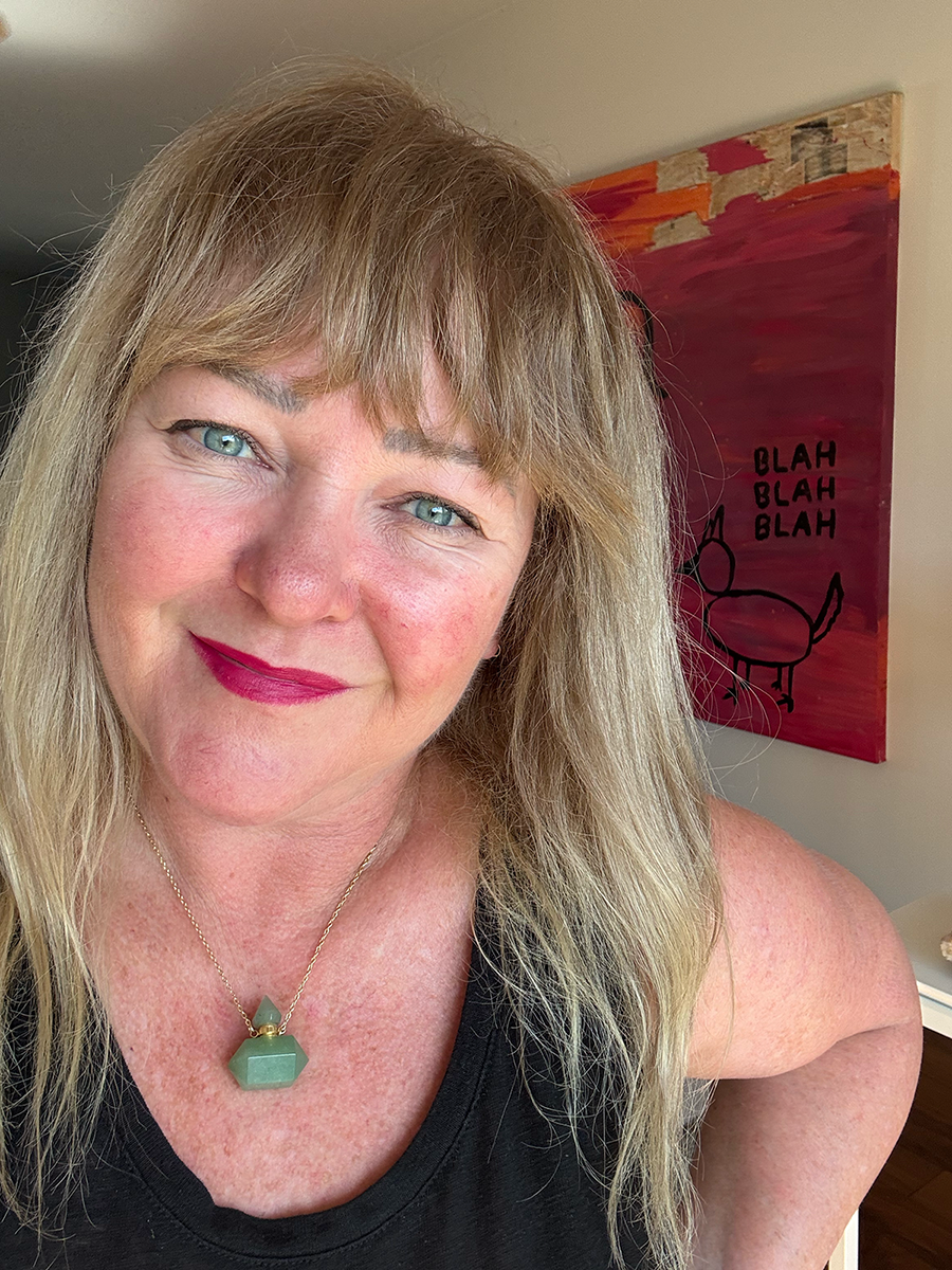 Julia Gomelsky looking at the camera with her artwork in the background, a pink canvas with "blah blah blah" painted