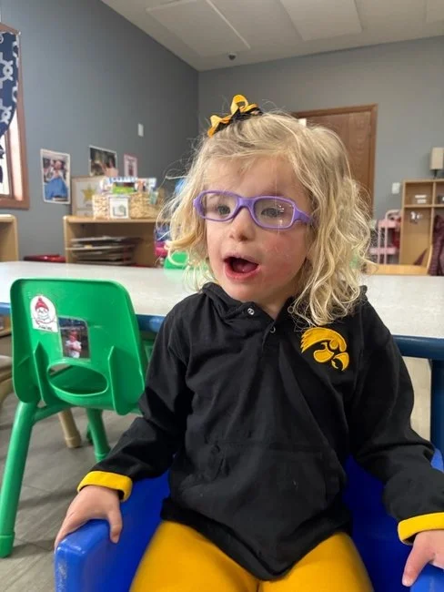 Rowan sitting in a blue chair in an Iowa Hawkeye's shirt