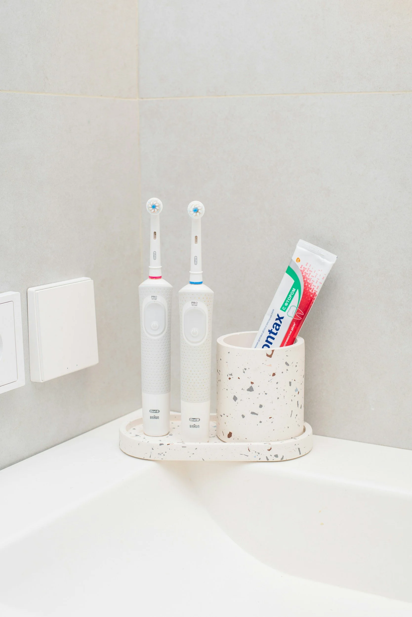 two electric toothbrushes sitting on a sink