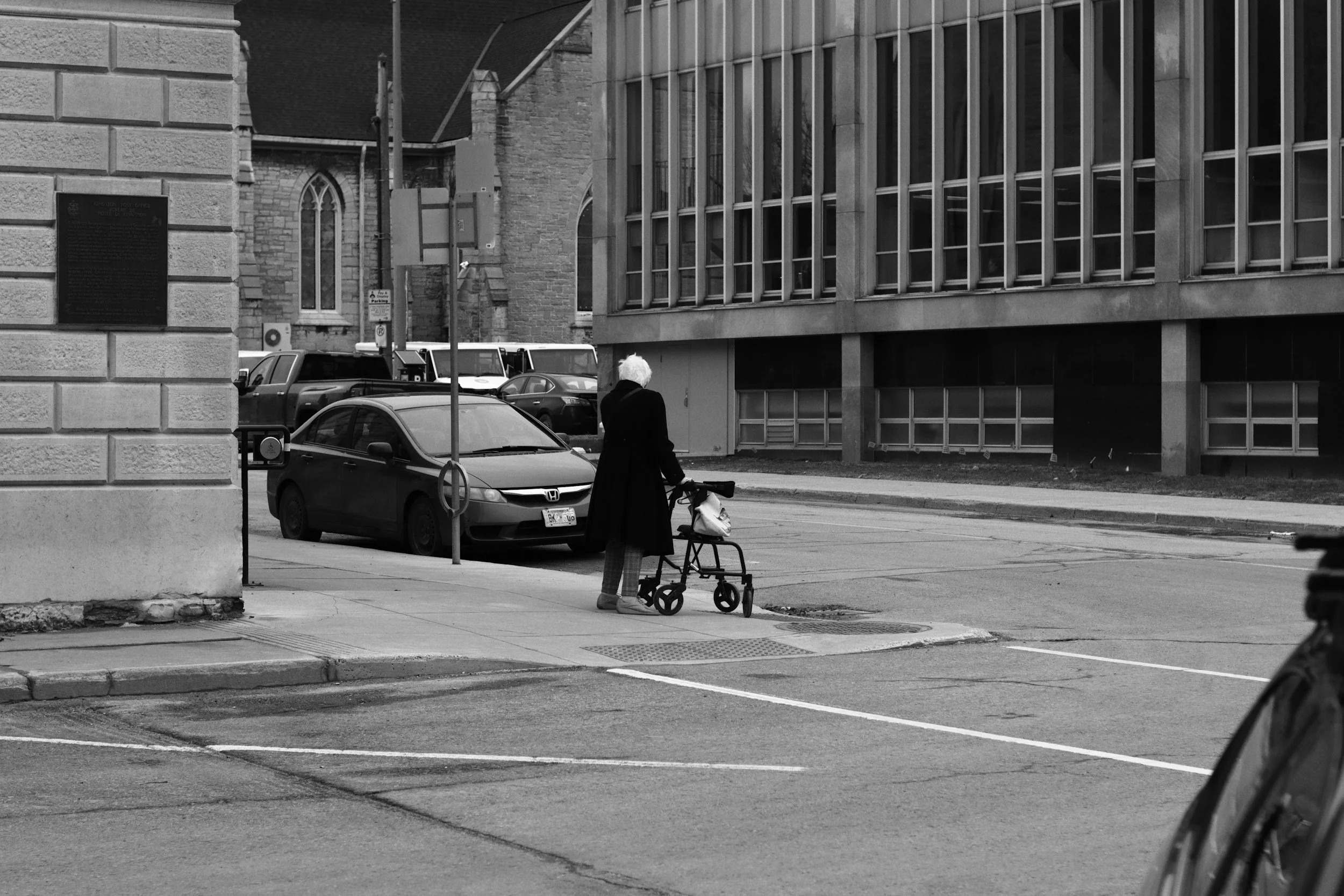 Someone using a curb cut to walk across the street with a rollator
