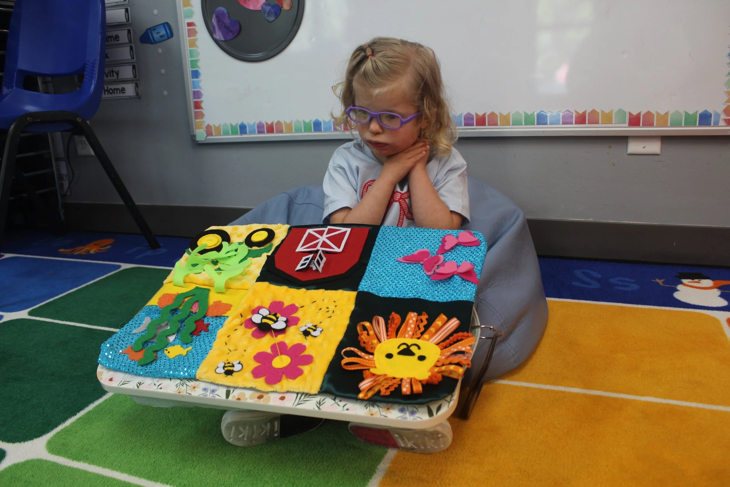 Rowan sitting on a bean bag chair with a sensory mat on her lap