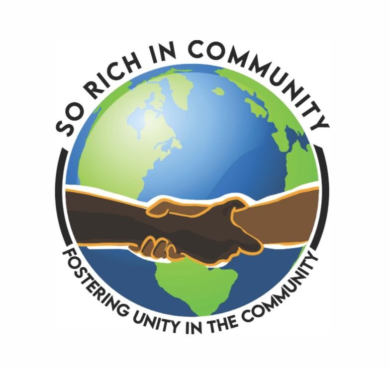 A logo featuring a globe with two hands shaking in front of it, surrounded by the text 'So Rich In Community' at the top and 'Fostering Unity in the Community' at the bottom.