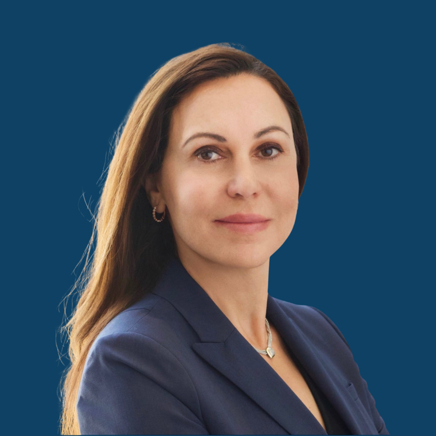 Professional woman with long brown hair, wearing a navy blazer, necklace, and earrings, posed against a dark blue background.