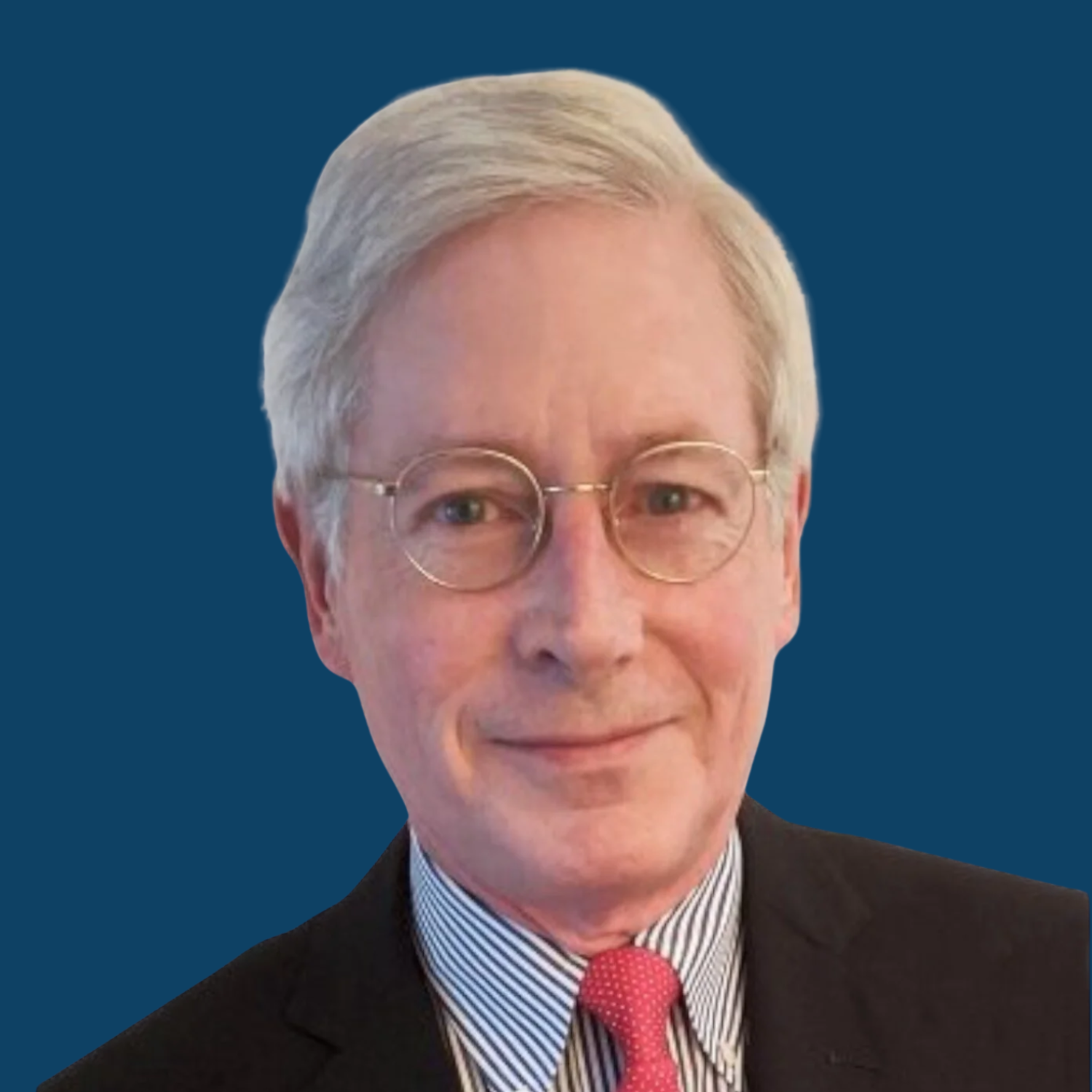 Portrait of a smiling man with gray hair, wearing glasses, a suit, and a red tie, against a dark blue background.