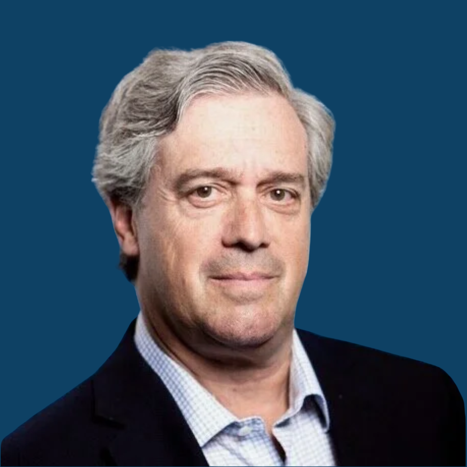 Photograph of a middle-aged man with gray hair, wearing a dark blazer and a checkered shirt, against a solid dark blue background.
