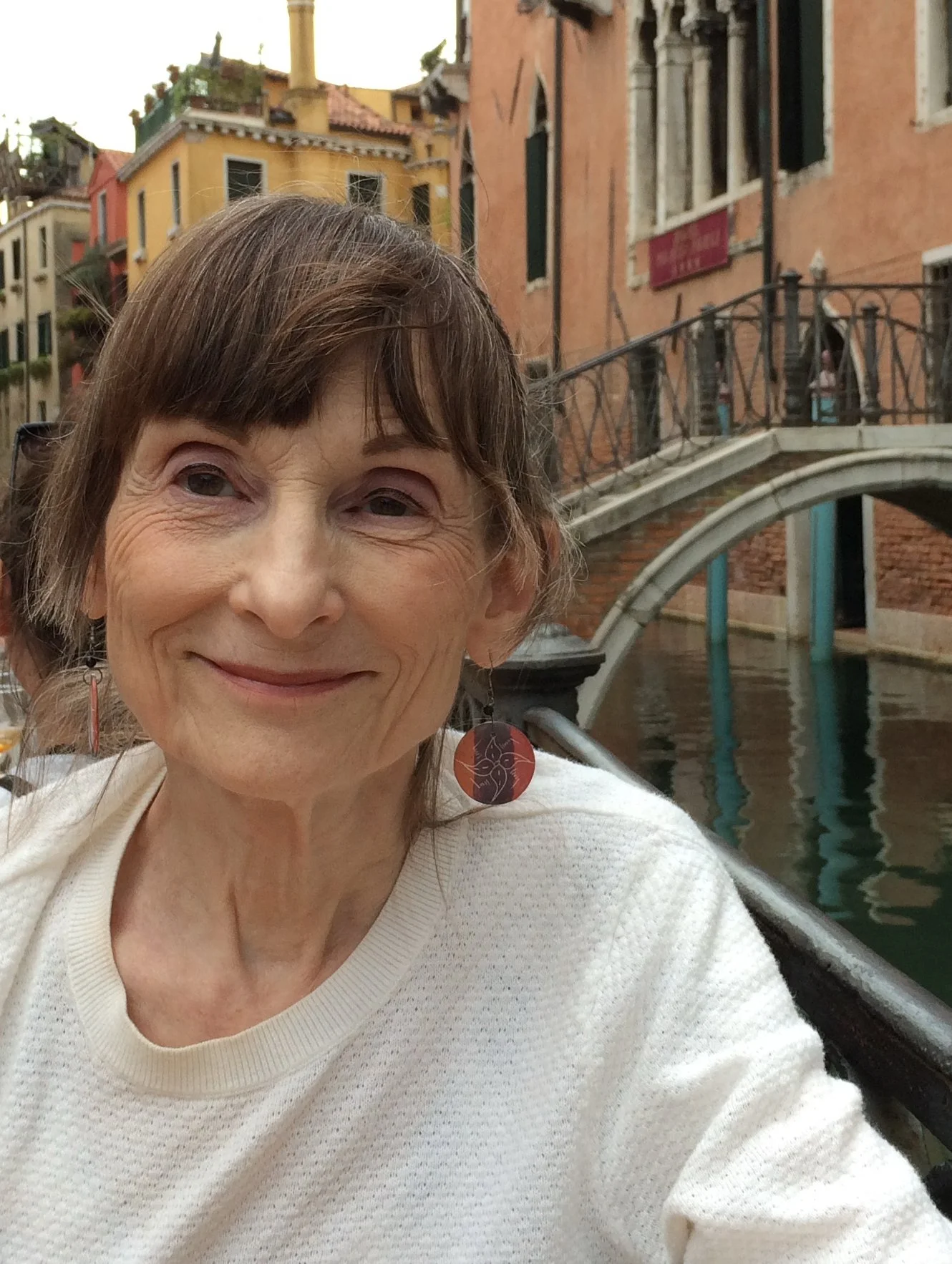 Headshot photograph of the author with a Venice canal scene behind her.