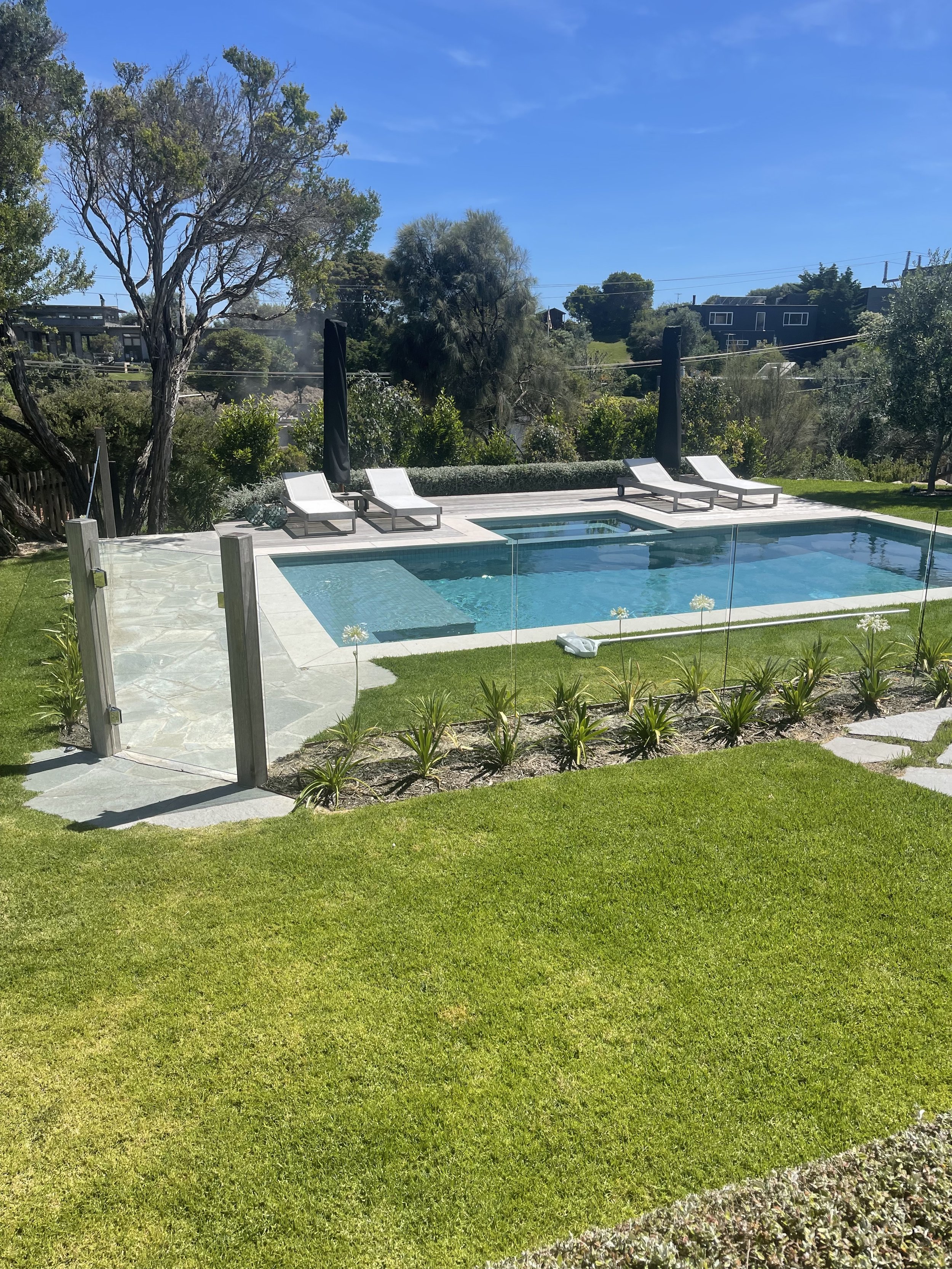 A stunning outdoor pool area with sparkling clean glass panels.
