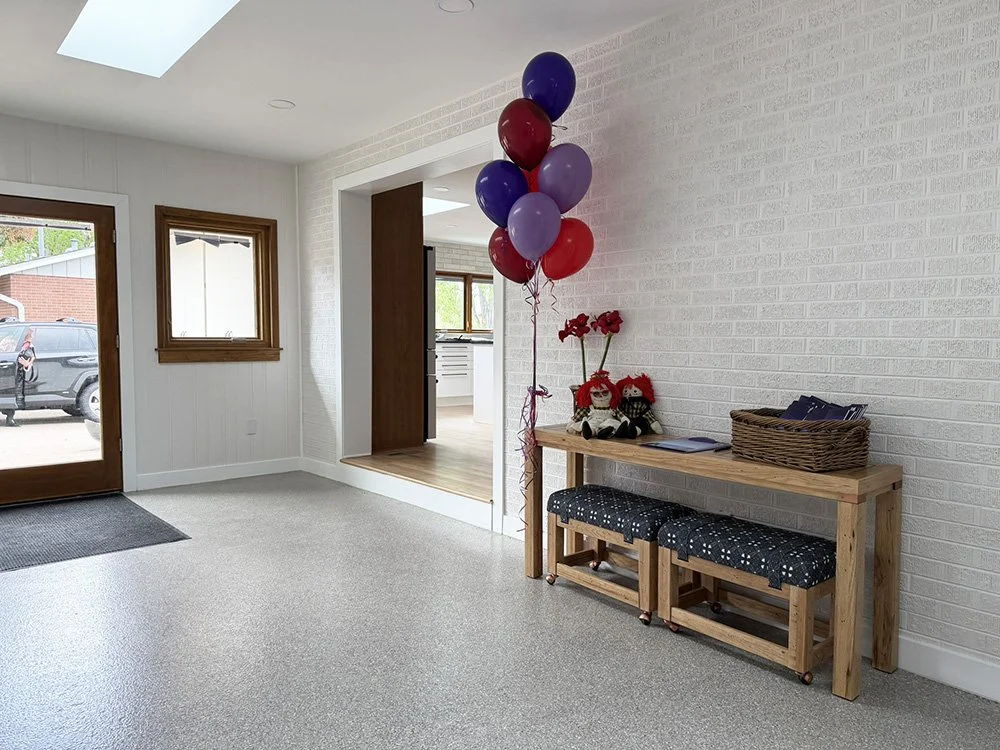 The breezeway floor has plenty of space for  transfers. The slightly rough epoxy finish catches water, mud, and snow that might be tracked in on wheeled devices without becoming too slick.