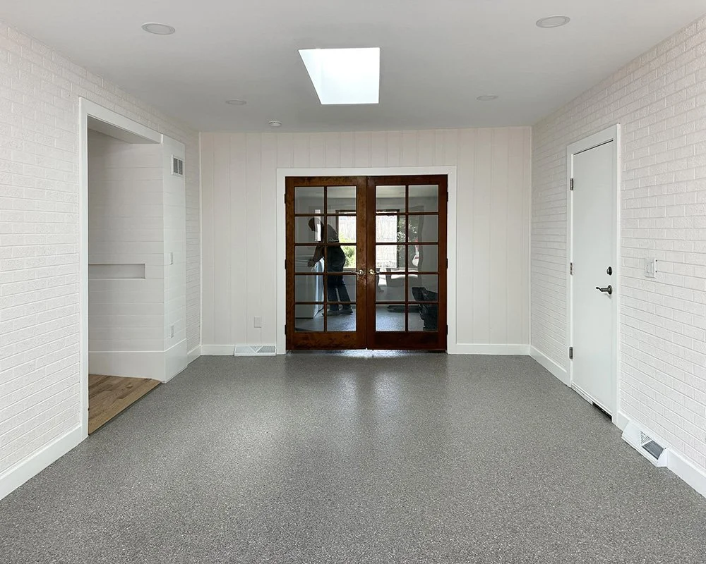 The laundry room is at the far end of the breezeway behind french doors. The door to the garage is on the right, the ramp to the main house is on the left. 