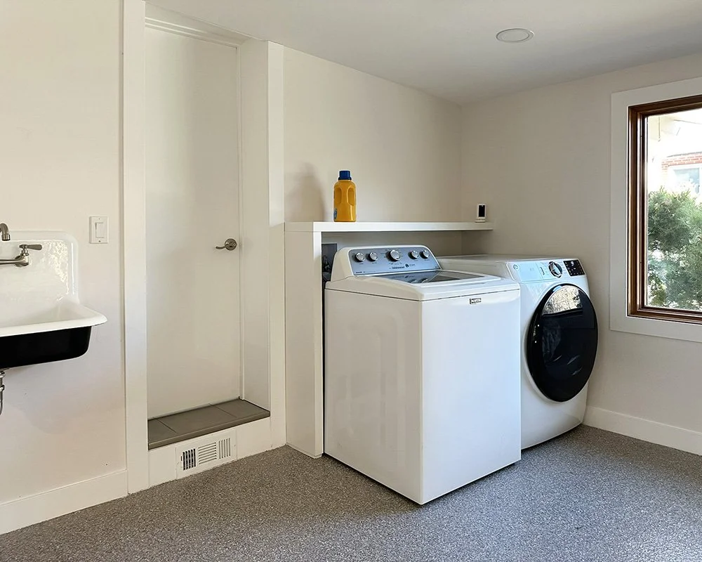 The laundry room has a washer and dryer and wall-hung utility sink. There's a narrow caregiver door that enters the primary bathroom. This is one of the few doors in the house that we were unable to make wheelchair accessible. 