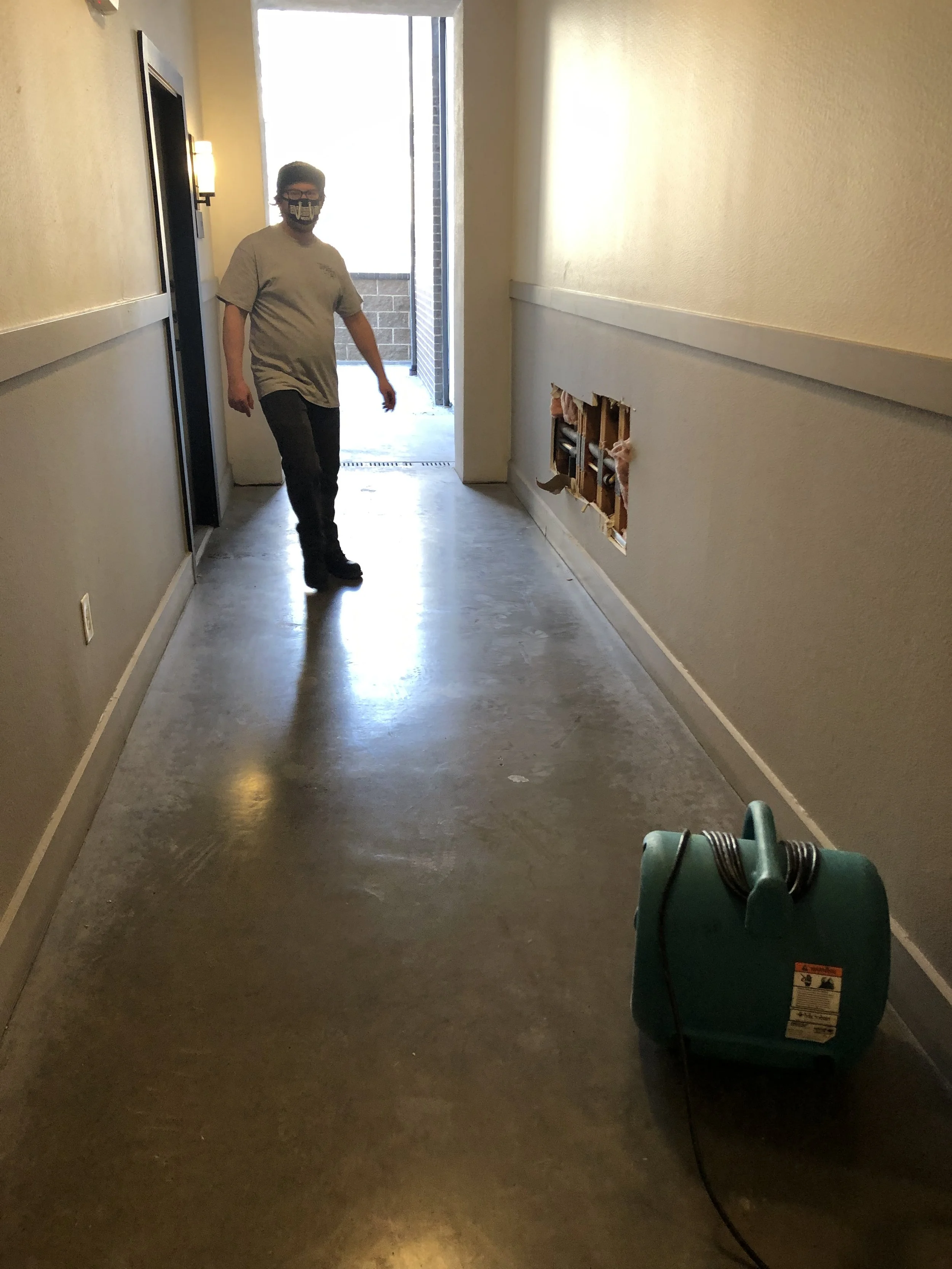 Drying down the baseboards and sill plates in the buildings hallway.