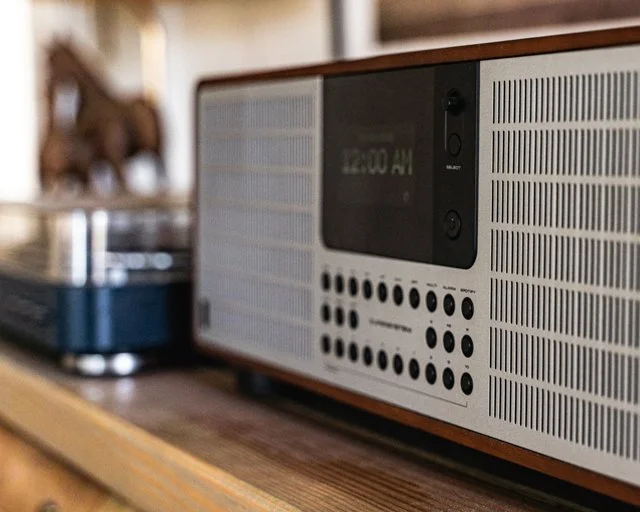 A vintage-style radio with a digital display on a wooden surface.
