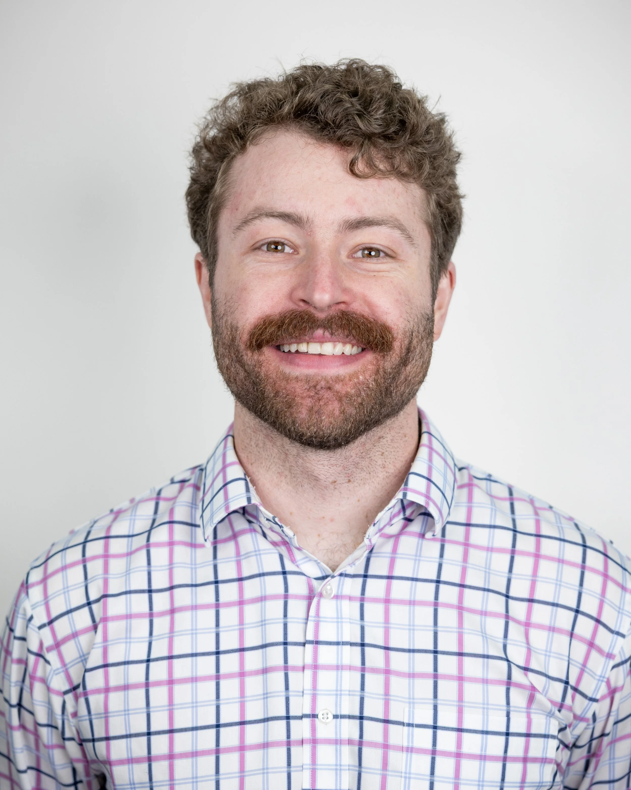 Man with a beard smiling, wearing a gray T-shirt.