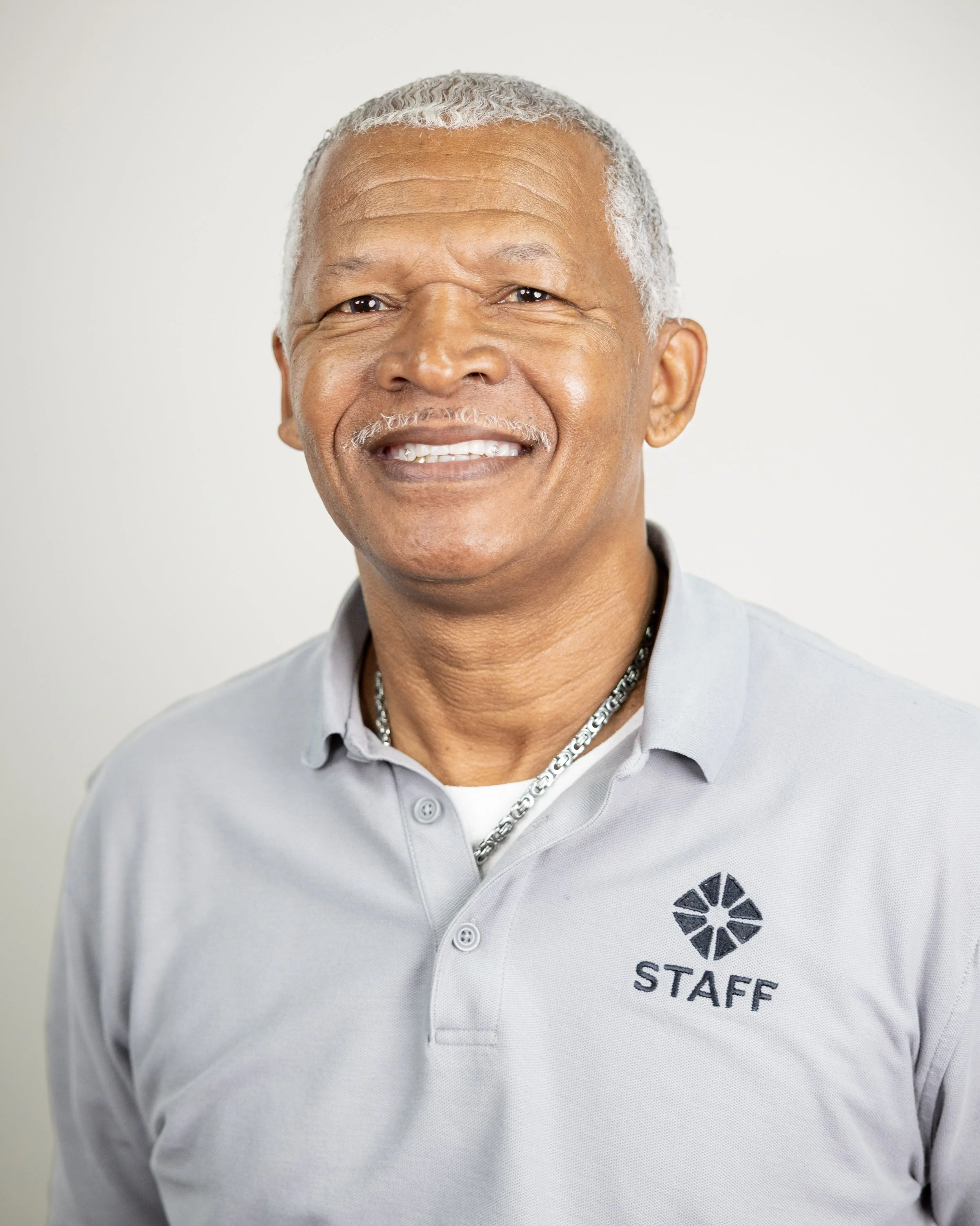 Man smiling with blue shirt and silver hair against a rustic blue wooden background