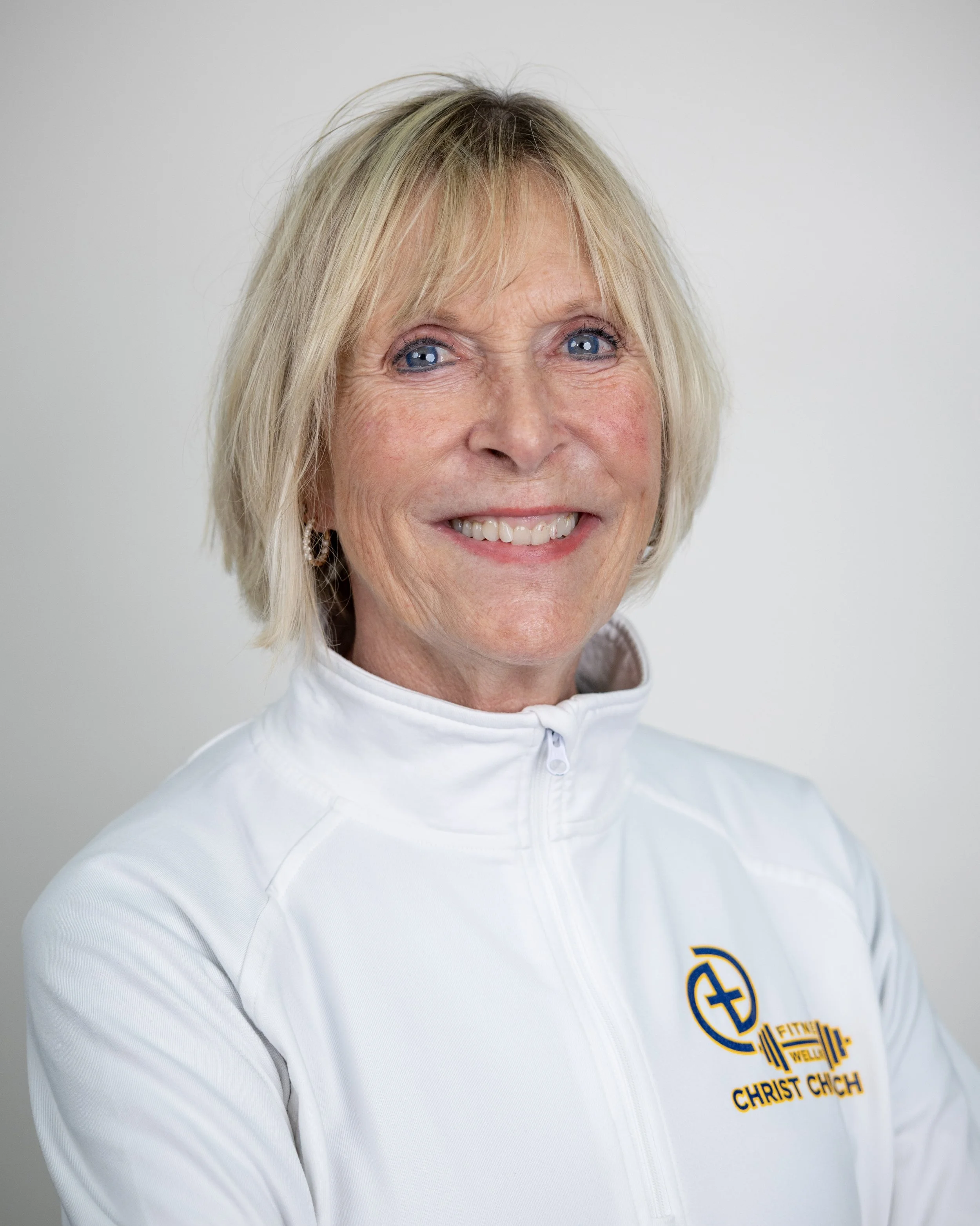 Smiling woman with blonde hair wearing a white turtleneck.