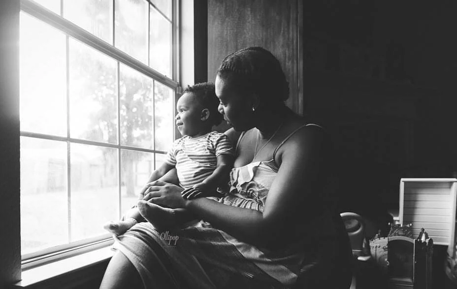 black mom and toddler boy looking out of window