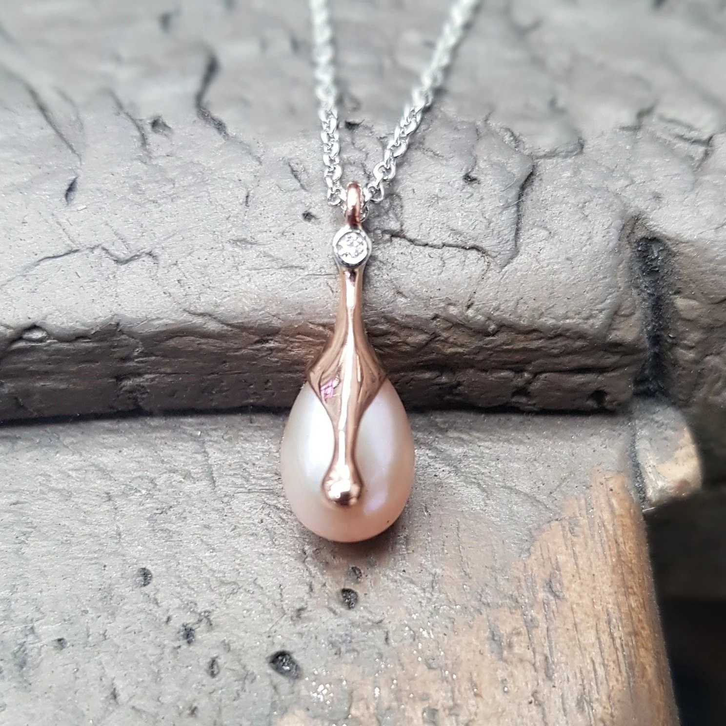 Pinky-peach coloured pearl! Perfect for this weather. This drop shaped fresh water pearl is set with a classic molten rose gold drip topped off with a diamond. We've paired this with a platinum chain for a bit of contrast and to pick up on the white 