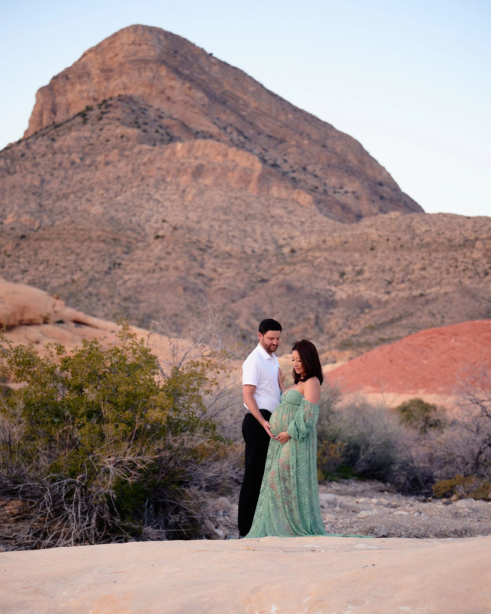 Sage lace gown against red sandstone, a couple close together in Red Rock Canyon outside Las Vegas.