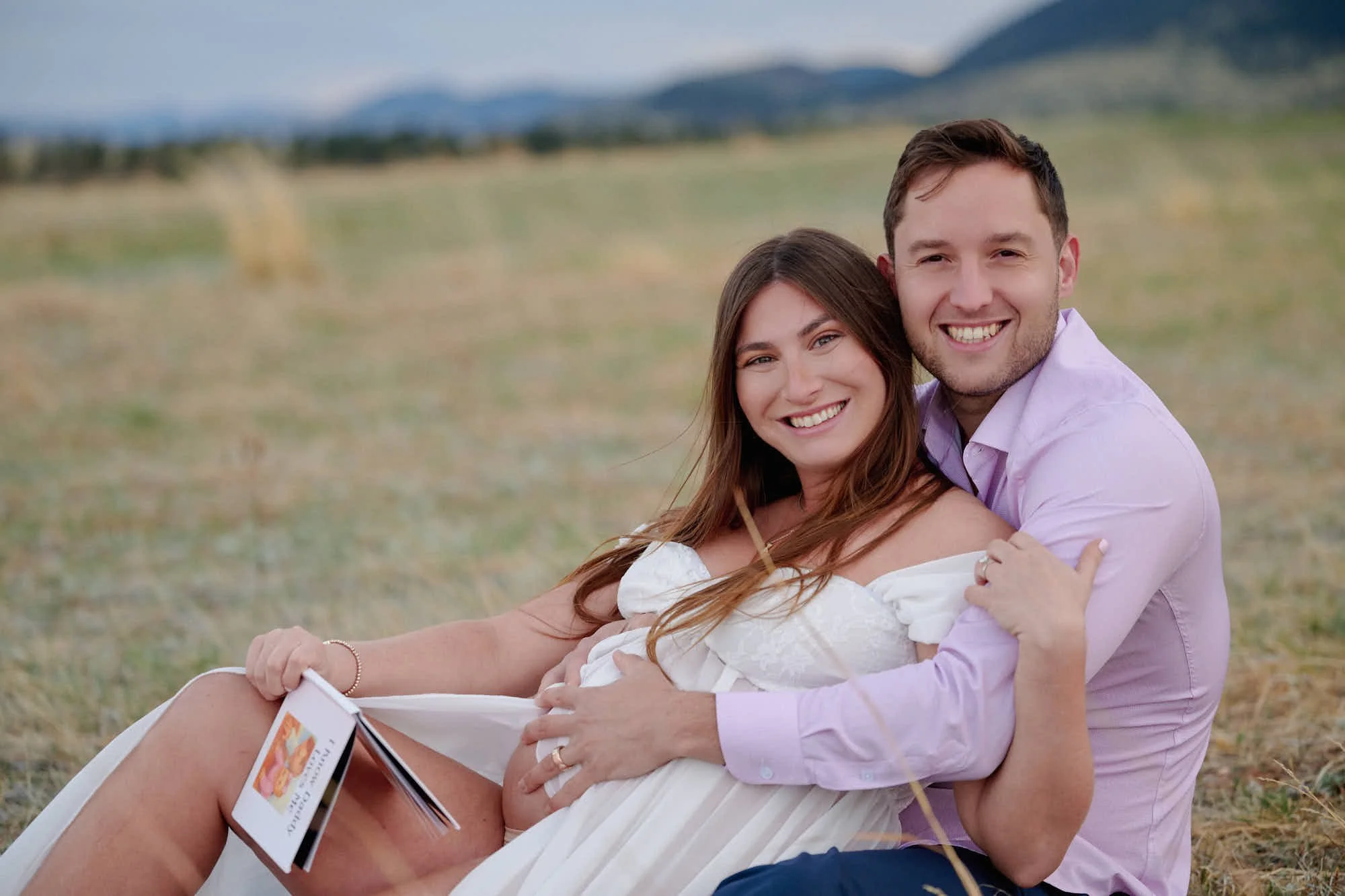 Expecting couple sitting close together, looking down at an ultrasound photo between them.