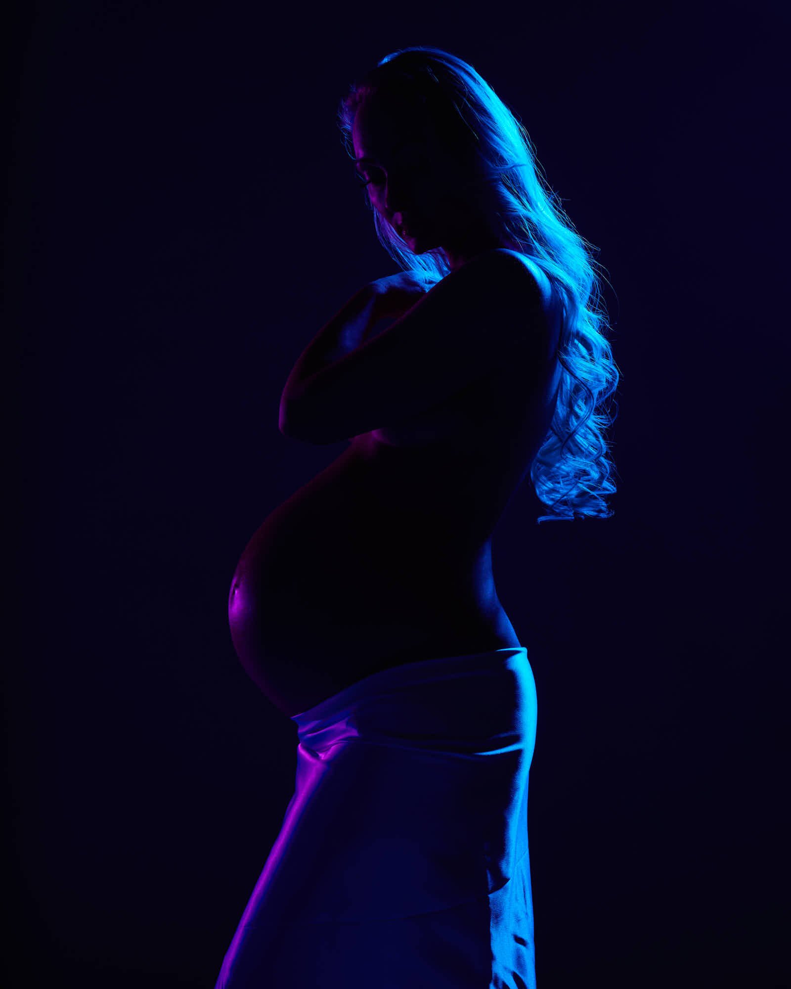 White satin skirt under blue and magenta gels, arms crossed in silhouette.