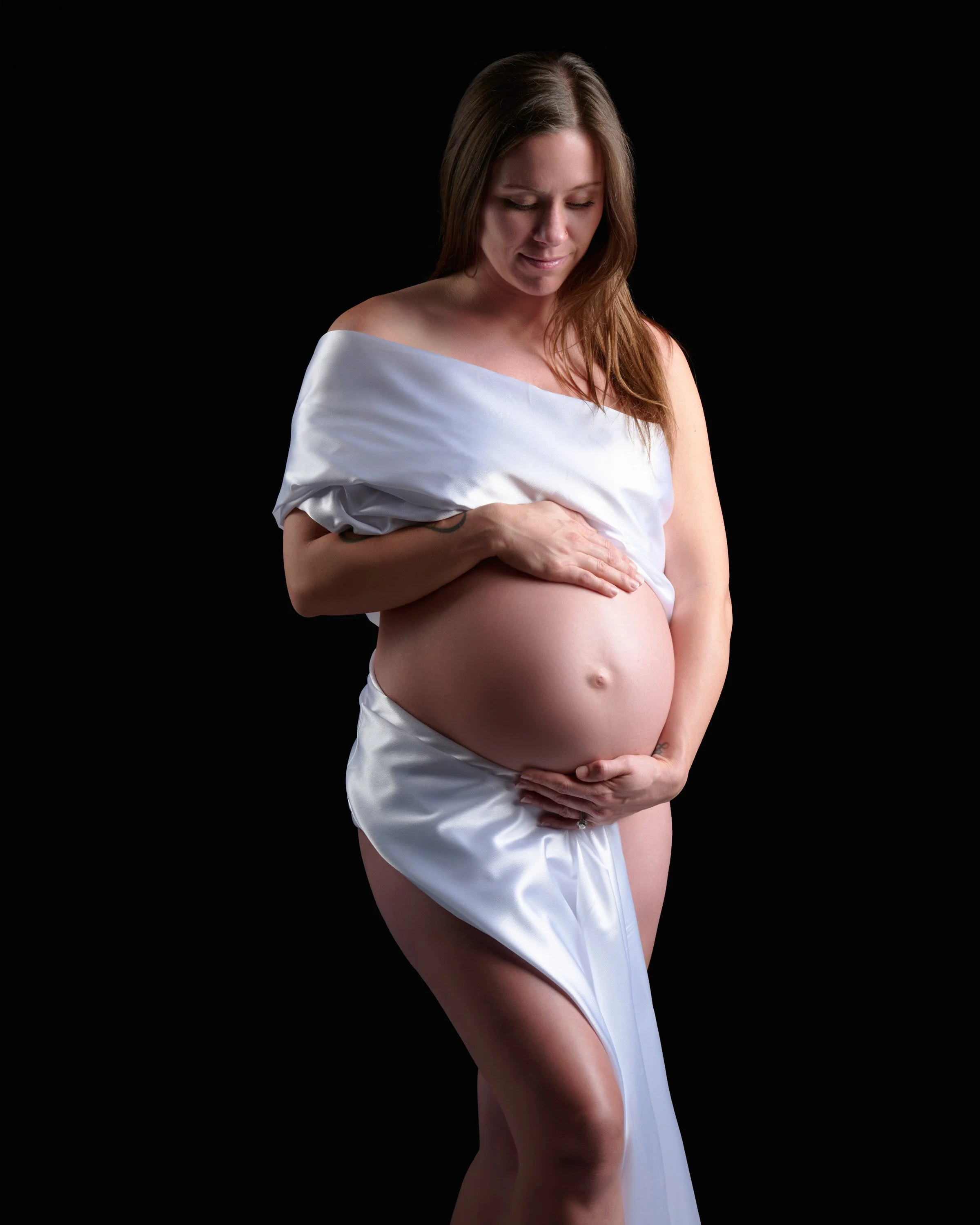 Soft white satin draped off the shoulders against a black backdrop.