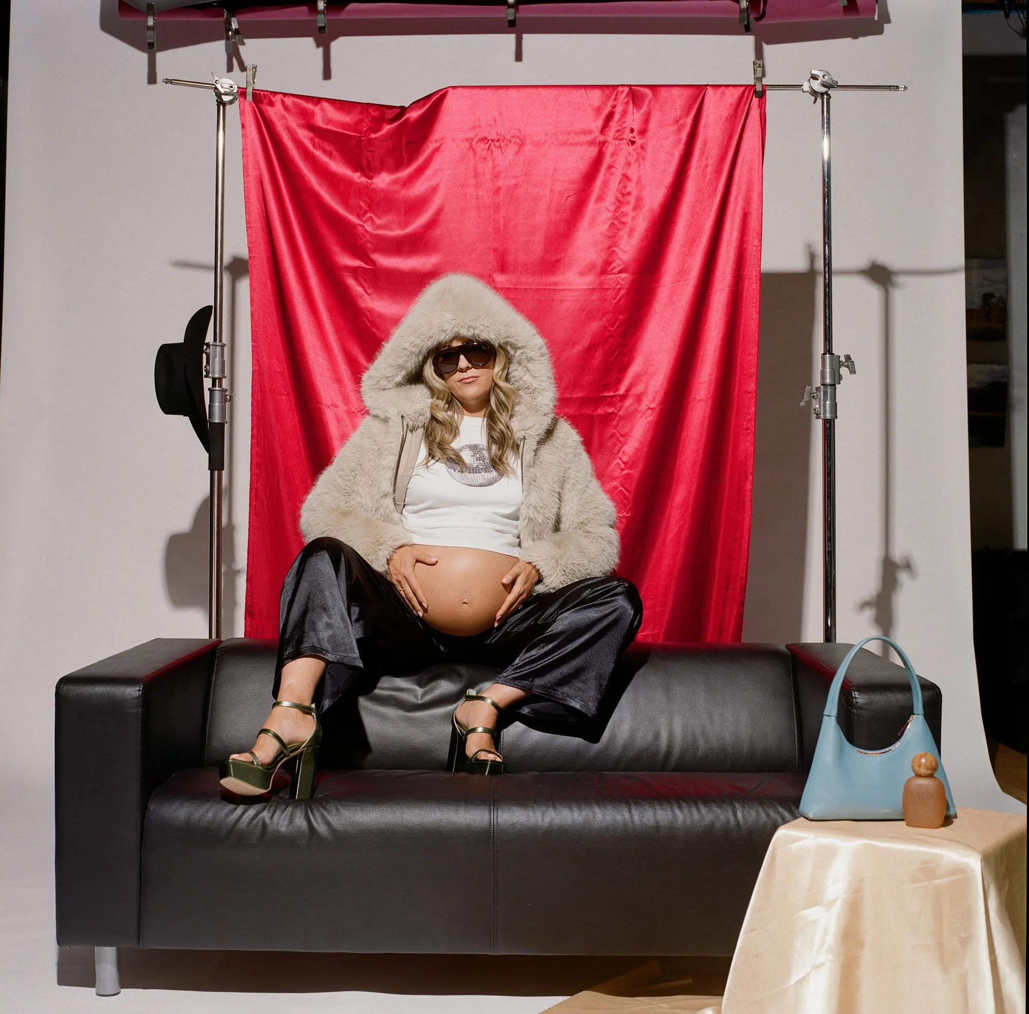 White fur hood and sunglasses on a black sofa, red backdrop and rigging in the Denver, Colorado studio.