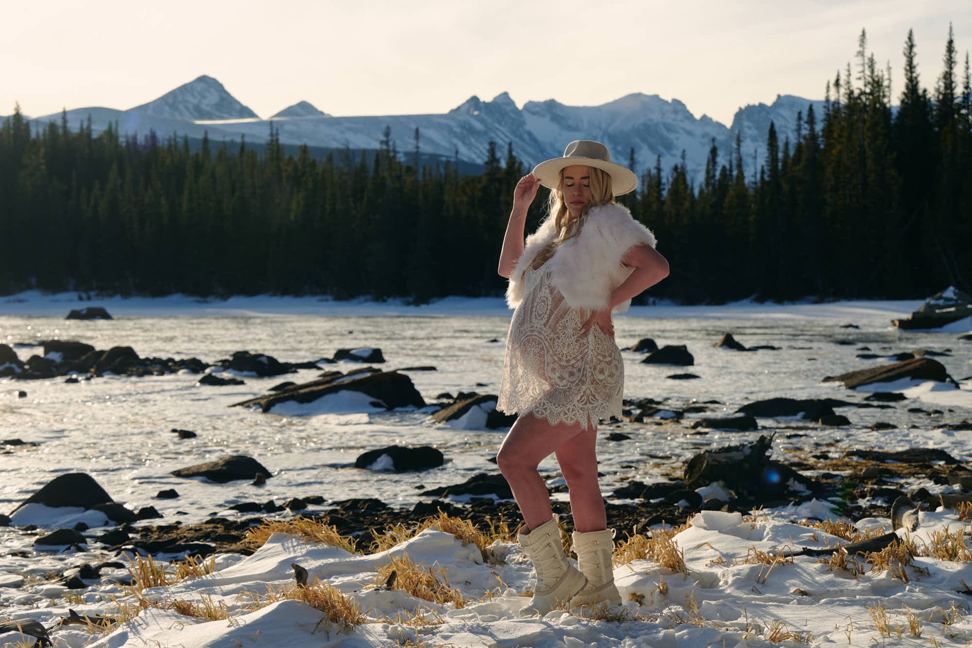 Snow maternity photos on a frozen lakeshore, ivory lace dress, fur stole and a wide-brim hat.