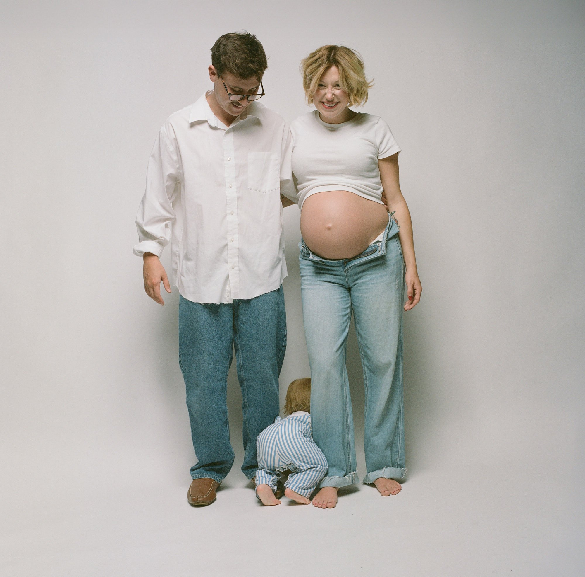 Expecting mother and her husband laughing together during a Denver studio maternity session.