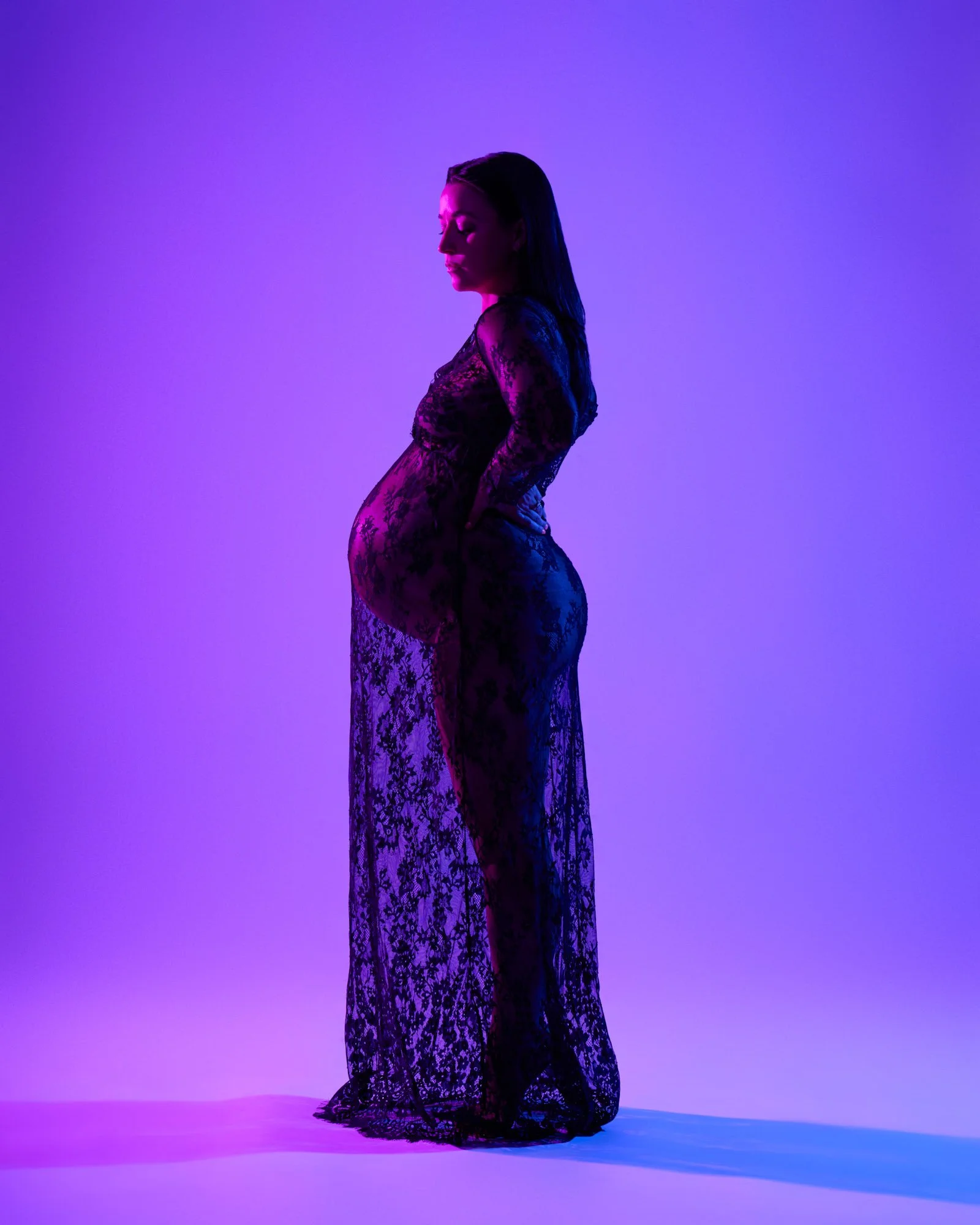 Black lace gown in profile against a violet gel backdrop in the Denver studio.