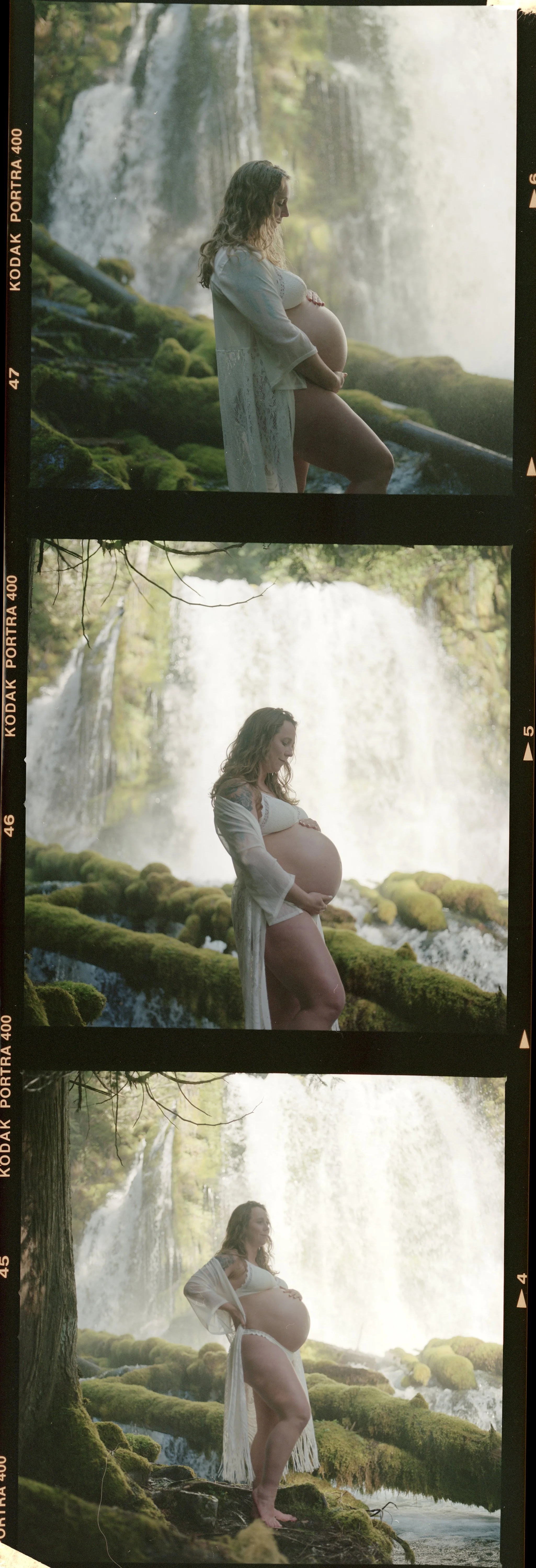 Three Portra frames on an uncut strip, a mother in sheer white on wet moss below a waterfall.