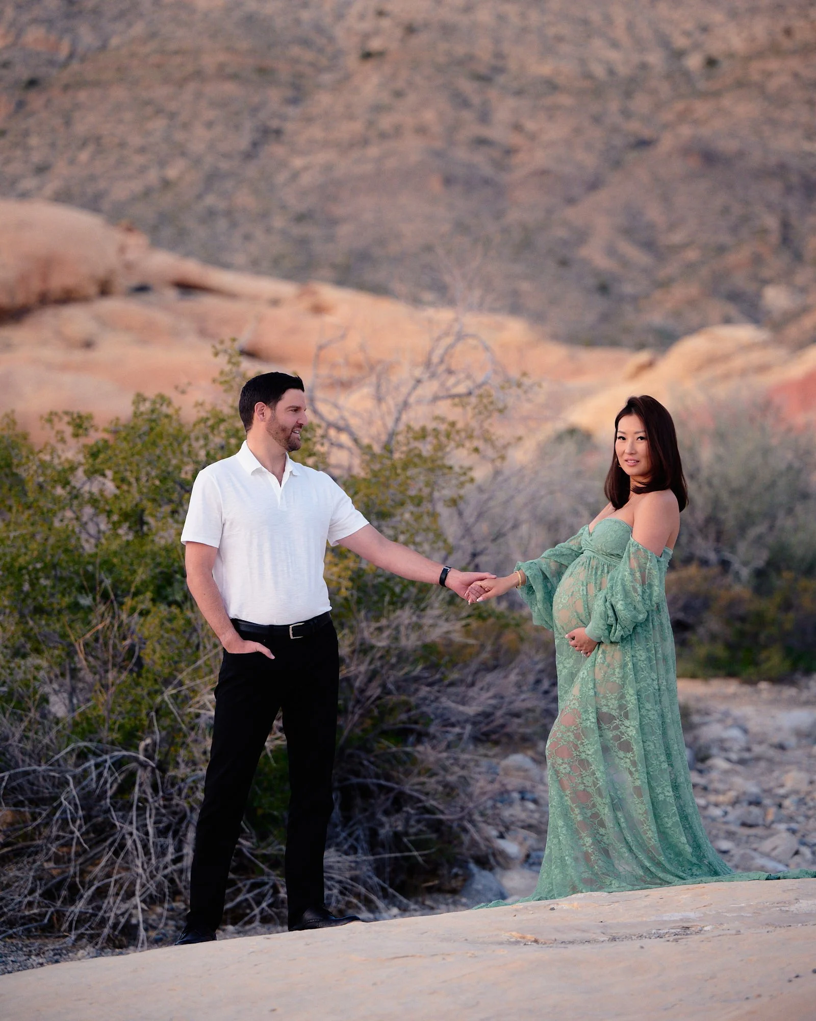 Holding hands across the sandstone, sage lace gown and desert brush outside Las Vegas.