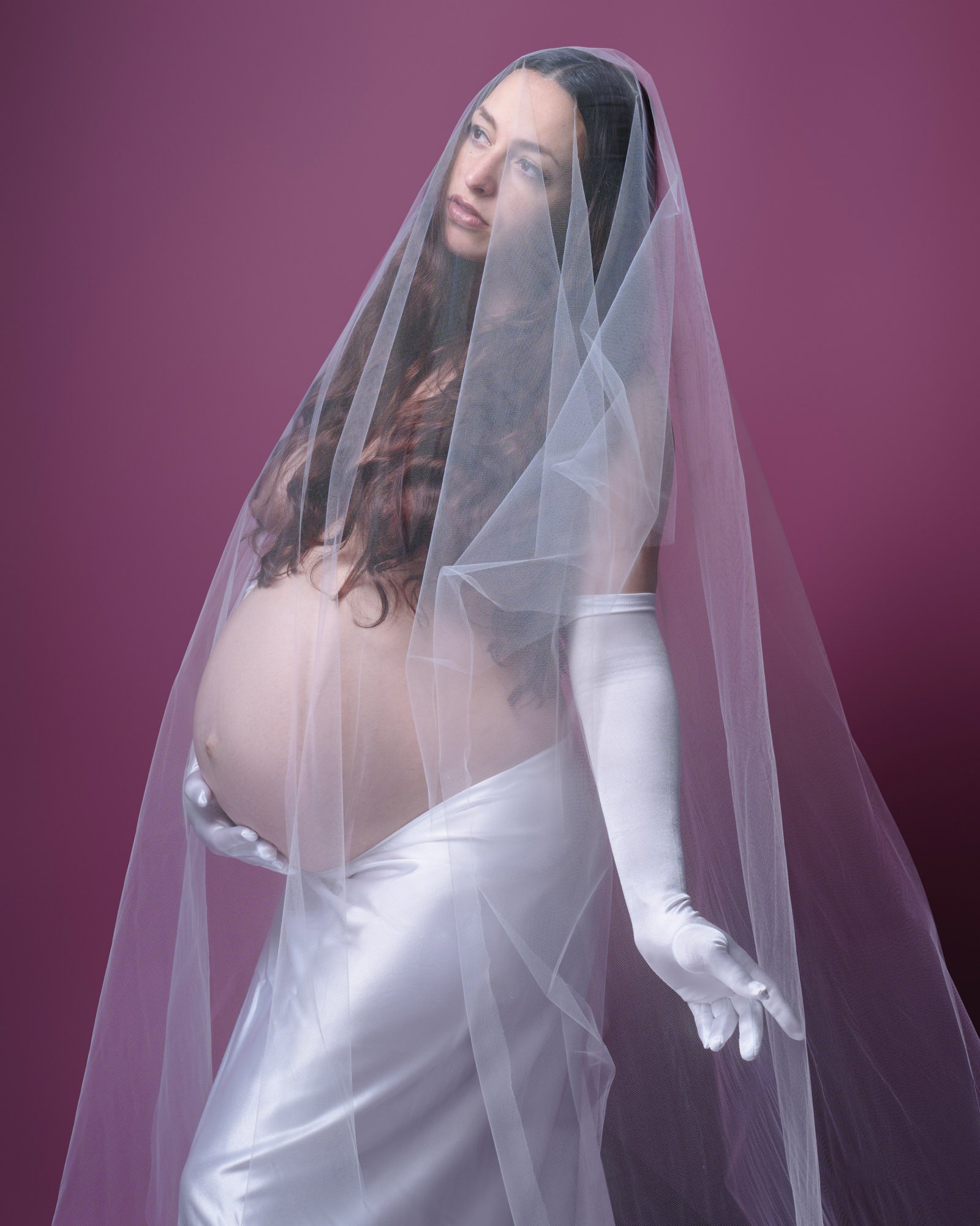 Long veil and opera gloves against a berry backdrop, boudoir maternity photography with a bridal twist.