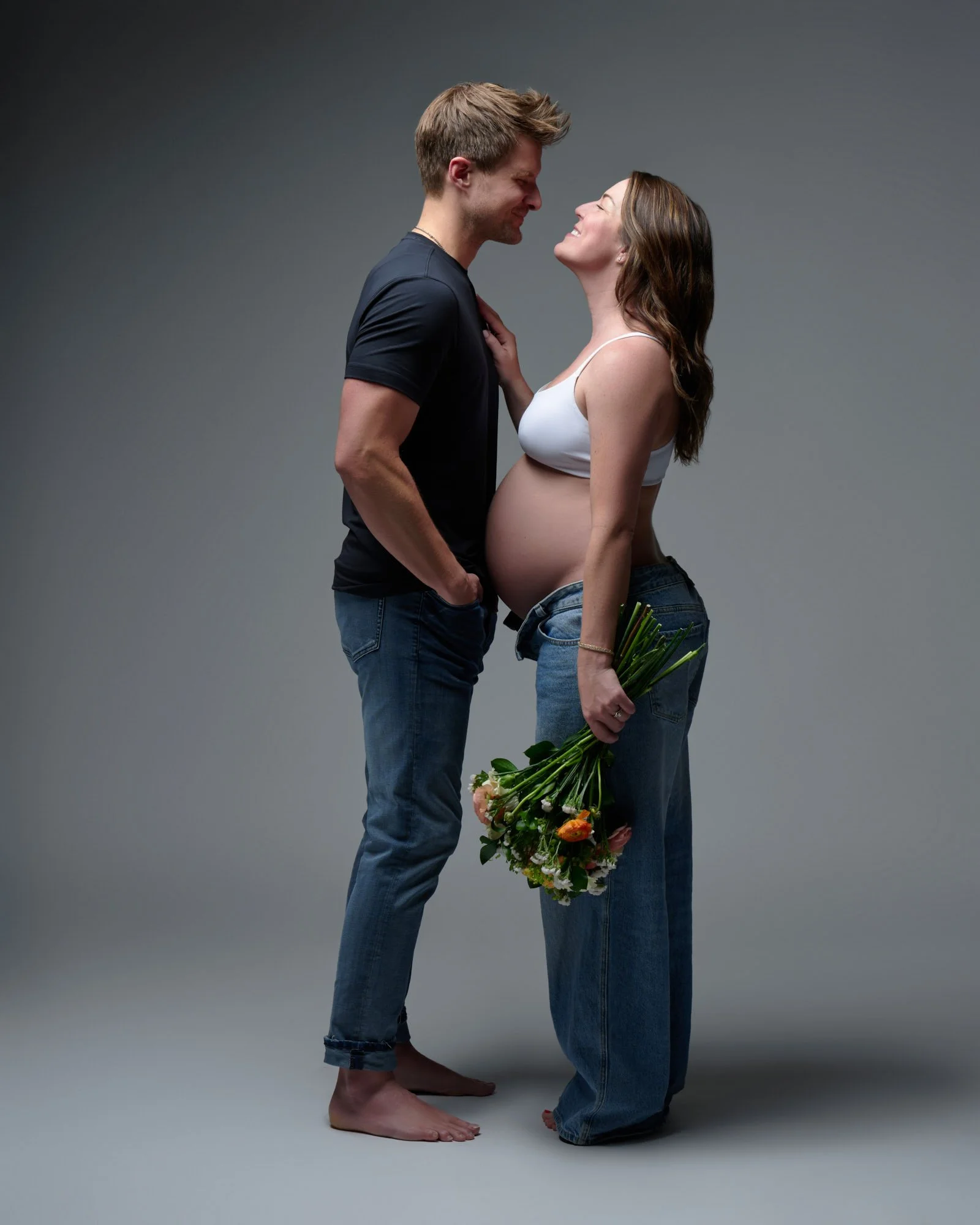 Expecting couple during a Denver maternity photography session, flowers at her side.