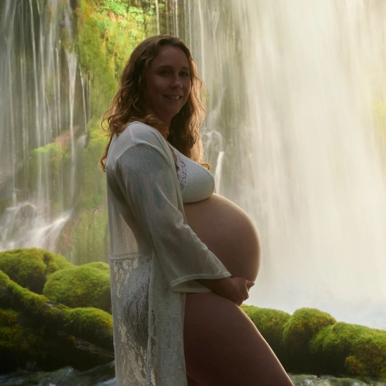 Bare bump framed by white lace, a curtain of waterfall filling the background.
