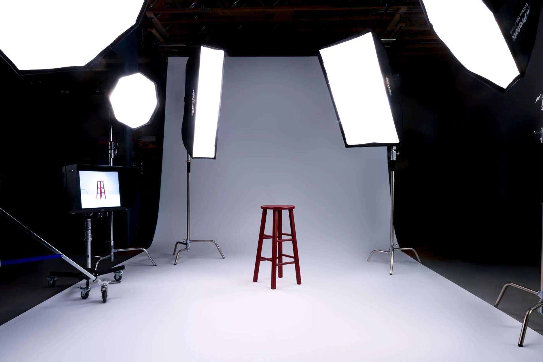 Inside the studio: white cyc wall, C-stands, and a red stool at 910 Santa Fe Drive, Denver.