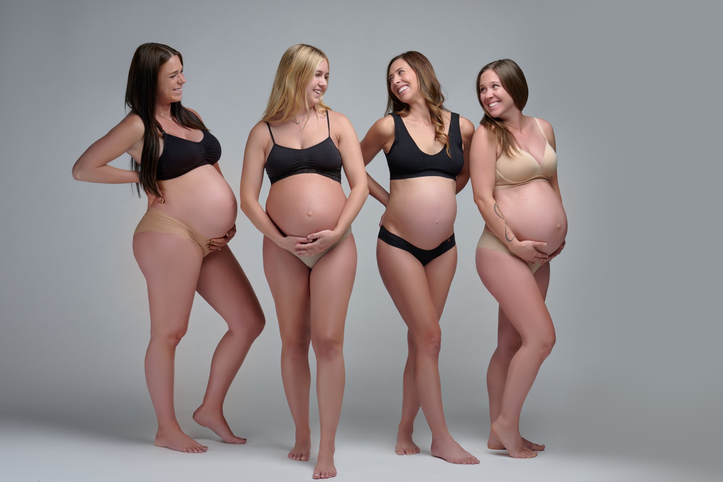 Studio photo of four pregnant women in bras and underwear posing together in Colorado
