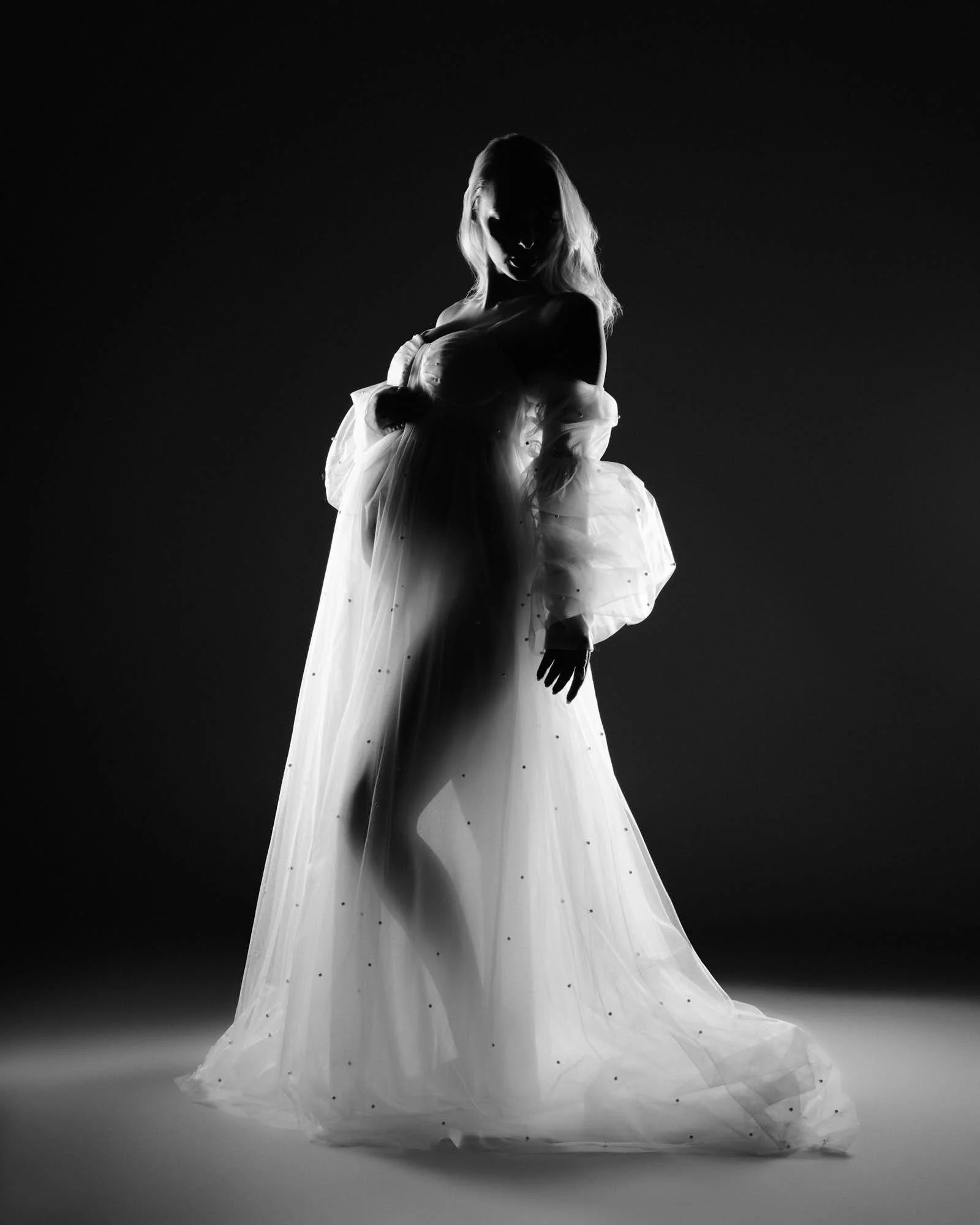 Black and white silhouette, sheer fabric billowing behind her.