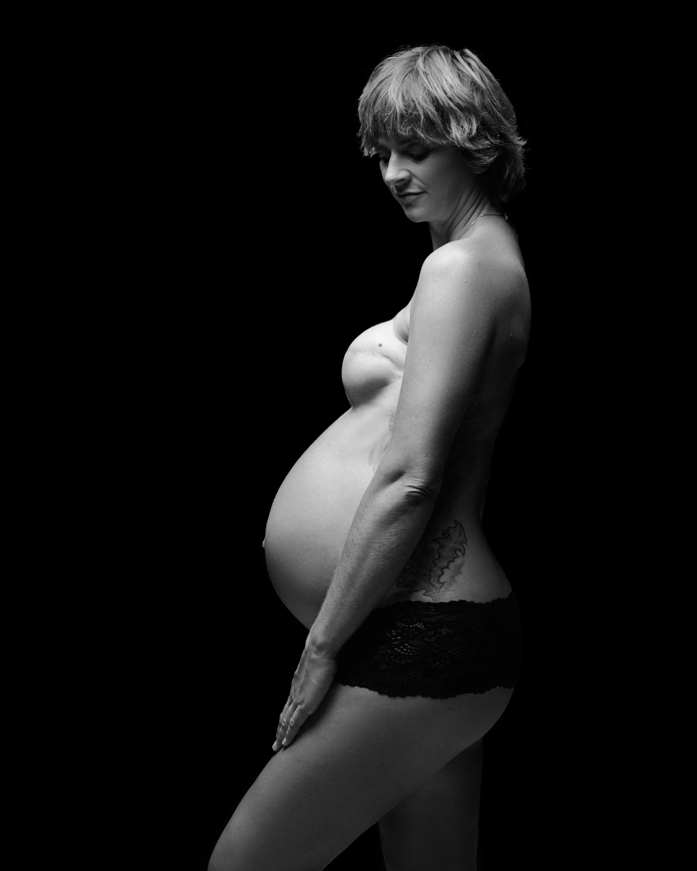 Black and white profile, short hair, half her form in shadow.